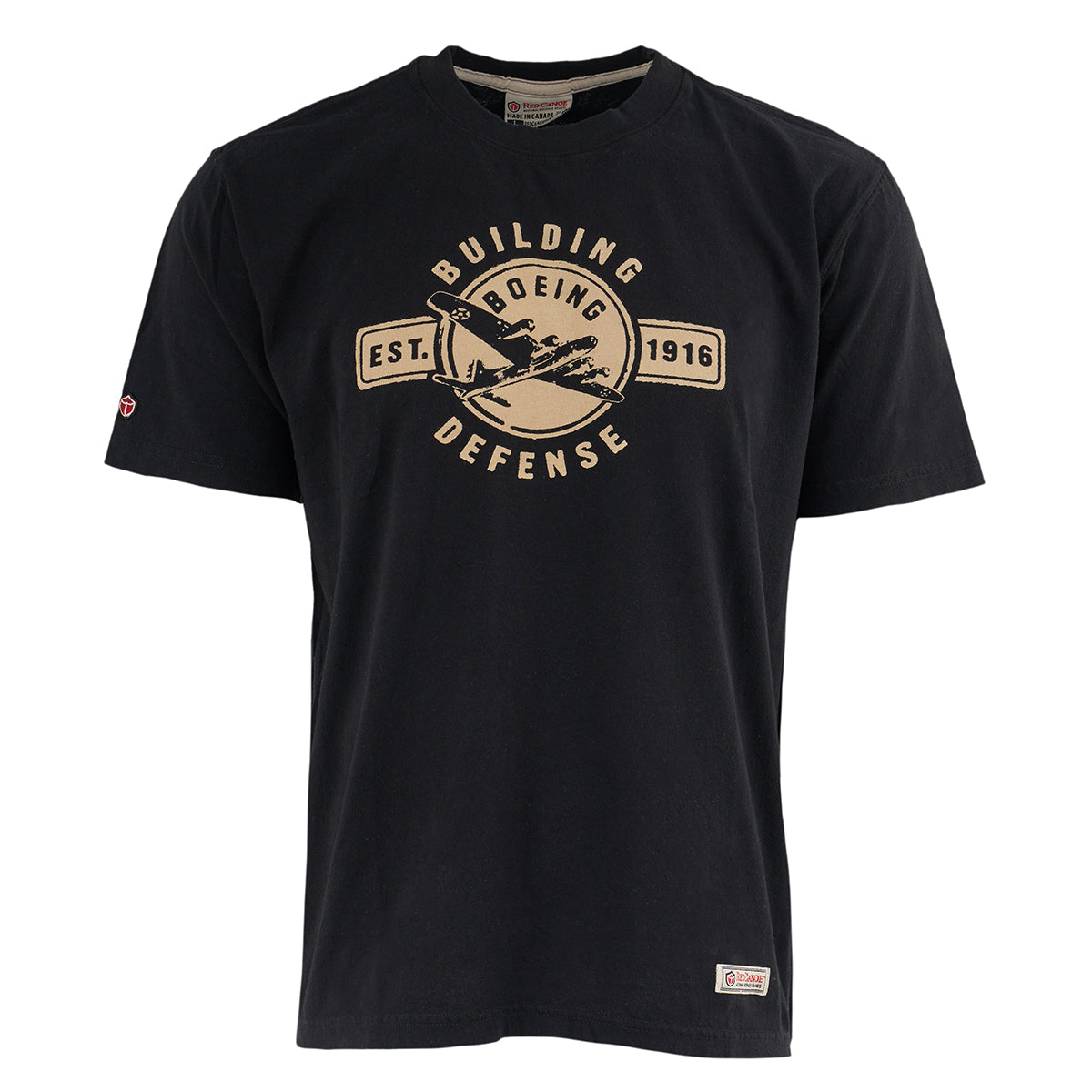 The Boeing Store’s Red Canoe Boeing Defense T-Shirt features a vintage beige “Boeing Building Defense Est. 1916” graphic with an aircraft illustration, inspired by classic WW2 tees. Short sleeves and crew neck included.