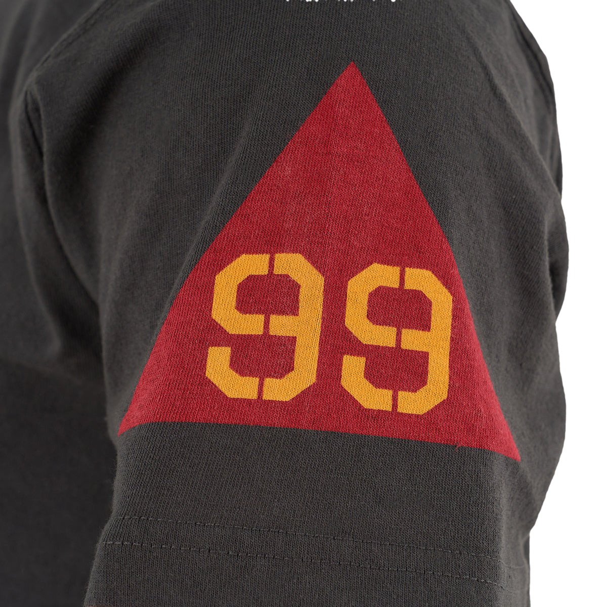 A close-up of The Boeing Store’s Red Canoe Boeing Tuskegee Airmen T-Shirt sleeve, showing a red triangle with yellow “99” on the upper arm—a nod to the legendary Tuskegee Airmen and their P-51 Mustang aircraft.