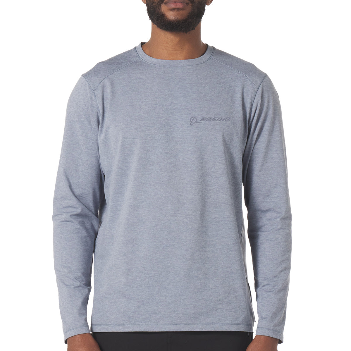 A man stands against a plain white background wearing the Glyder Boeing Men’s Dash Crewneck, a light gray lightweight long-sleeve top featuring the BOEING logo—ideal for a versatile wardrobe.