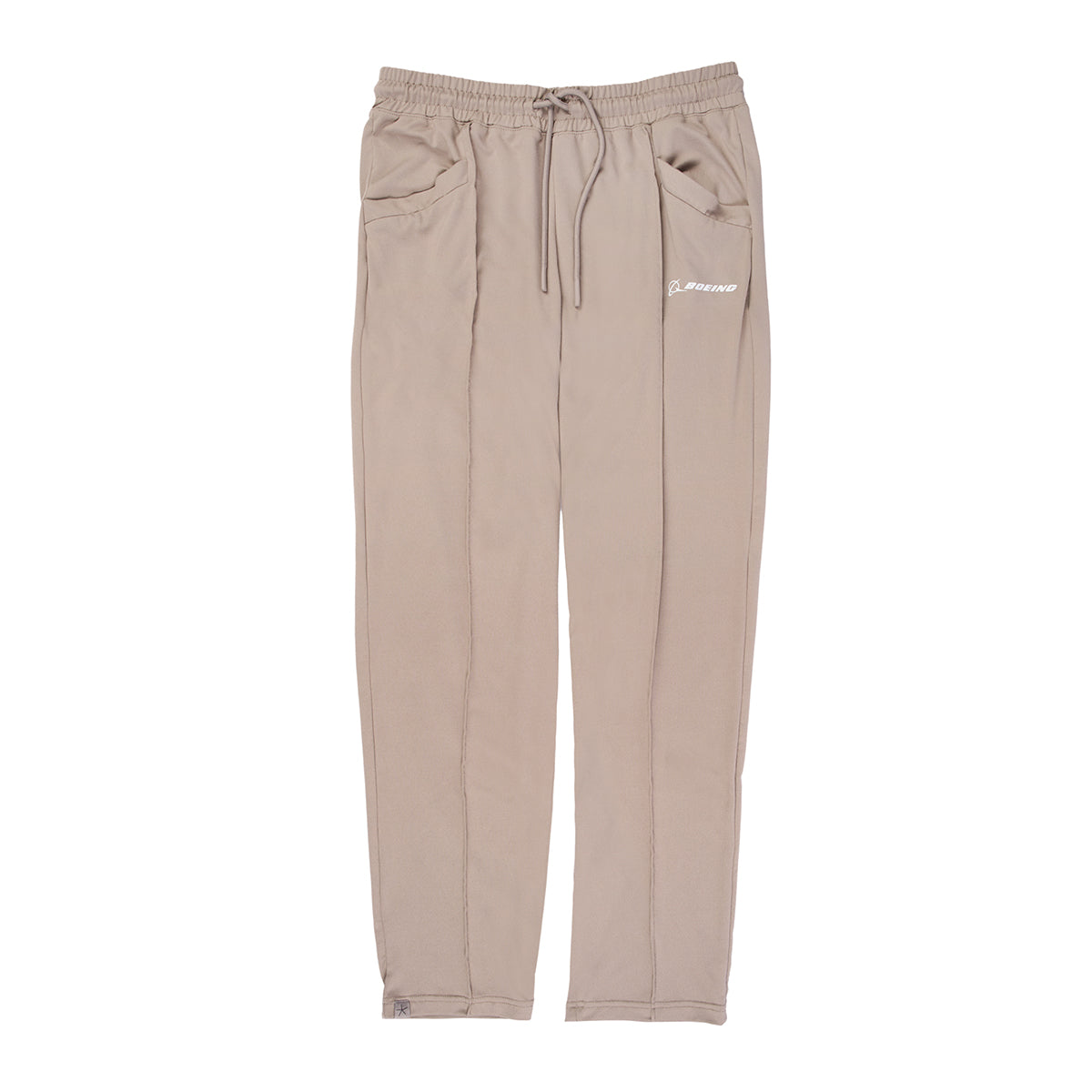 The Barefoot Dreams Boeing Women’s Butterchic Pintuck Pants by Boeing feature a light beige color, elastic waistband with drawstring, pintuck detailing, two front pockets, stitched seams, and a white embroidered logo on the left pocket.