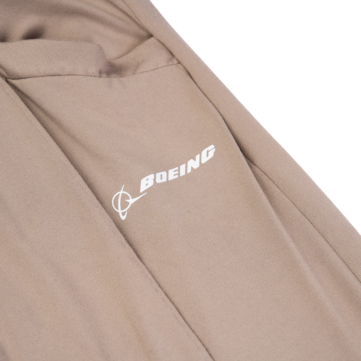 Close-up of Barefoot Dreams Boeing Women’s Butterchic Pintuck Pants in tan, featuring a white Boeing logo, pintuck detailing, visible seam, and pocket for effortless style.