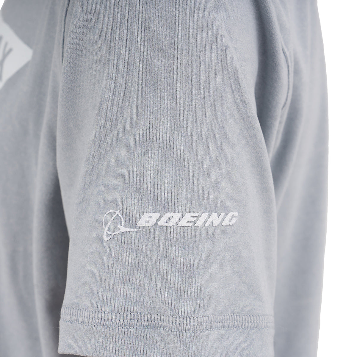 A close-up of the gray Boeing 737 MAX Velocity Kids’ Tech Stretch T-Shirt by BOEING, featuring a white Boeing logo and text on the sleeve inspired by the iconic aircraft.