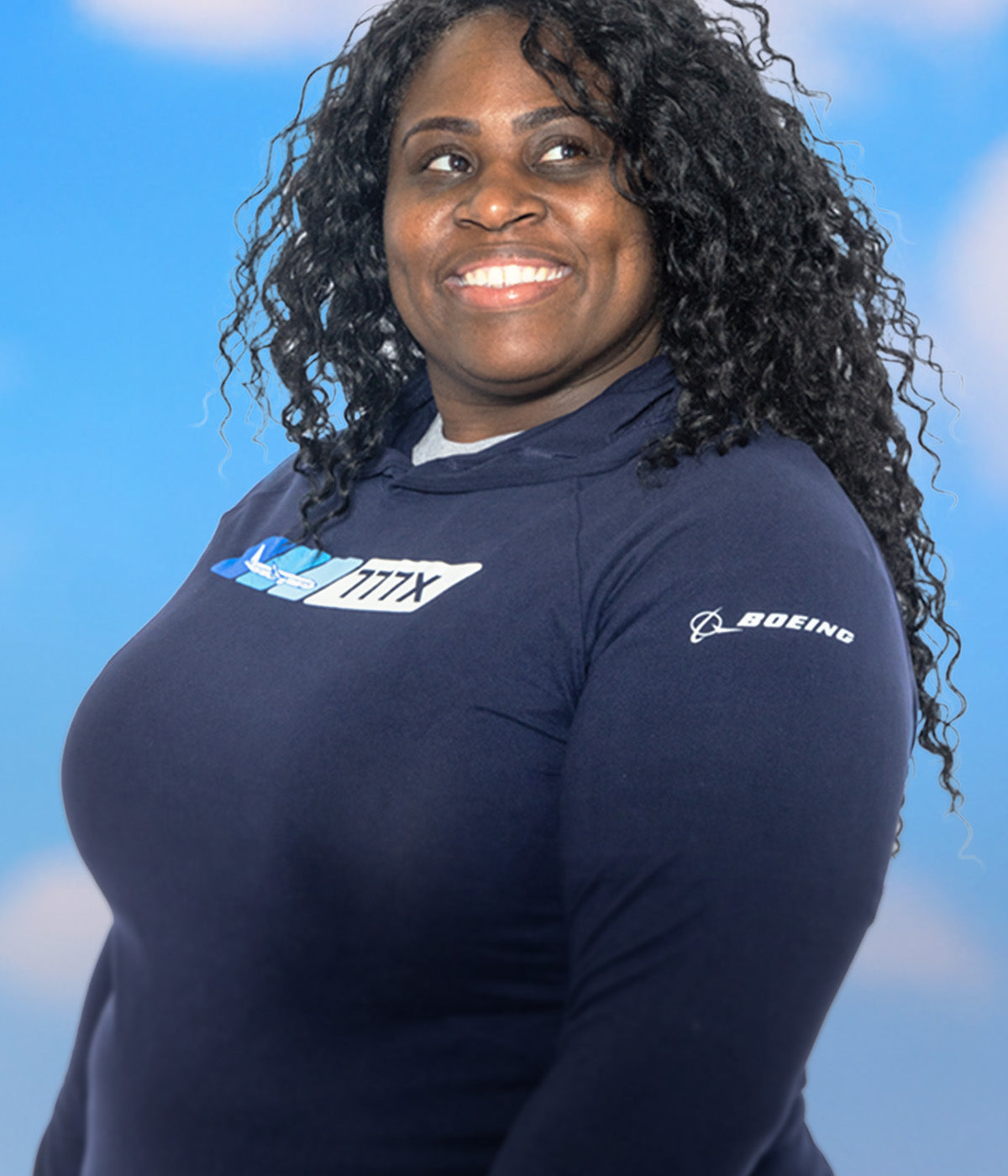 A female wearing a Boeing-branded navy blue shirt set against a blue sky background.