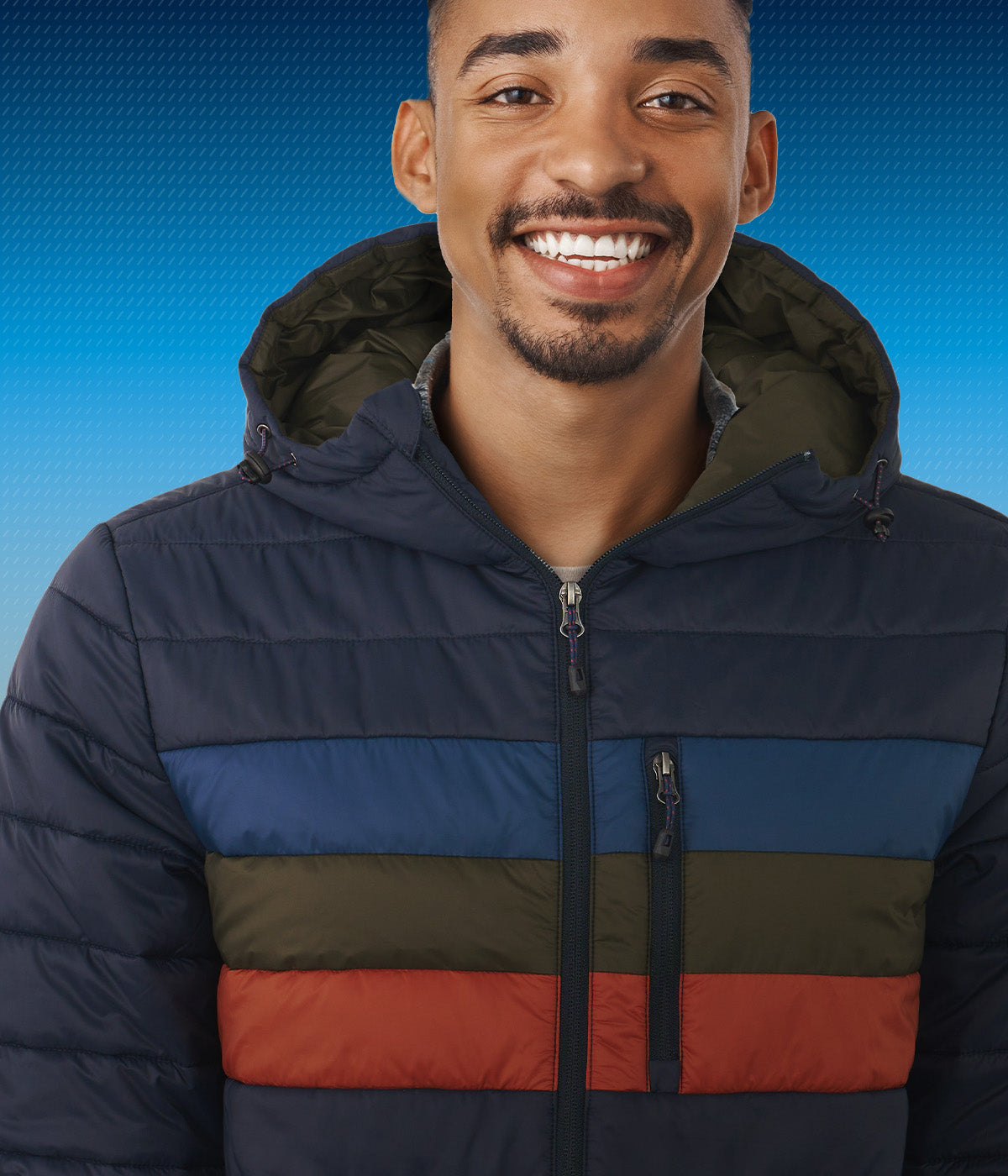 Man wearing a multicolored Boeing puffer jacket against a blue gradient background