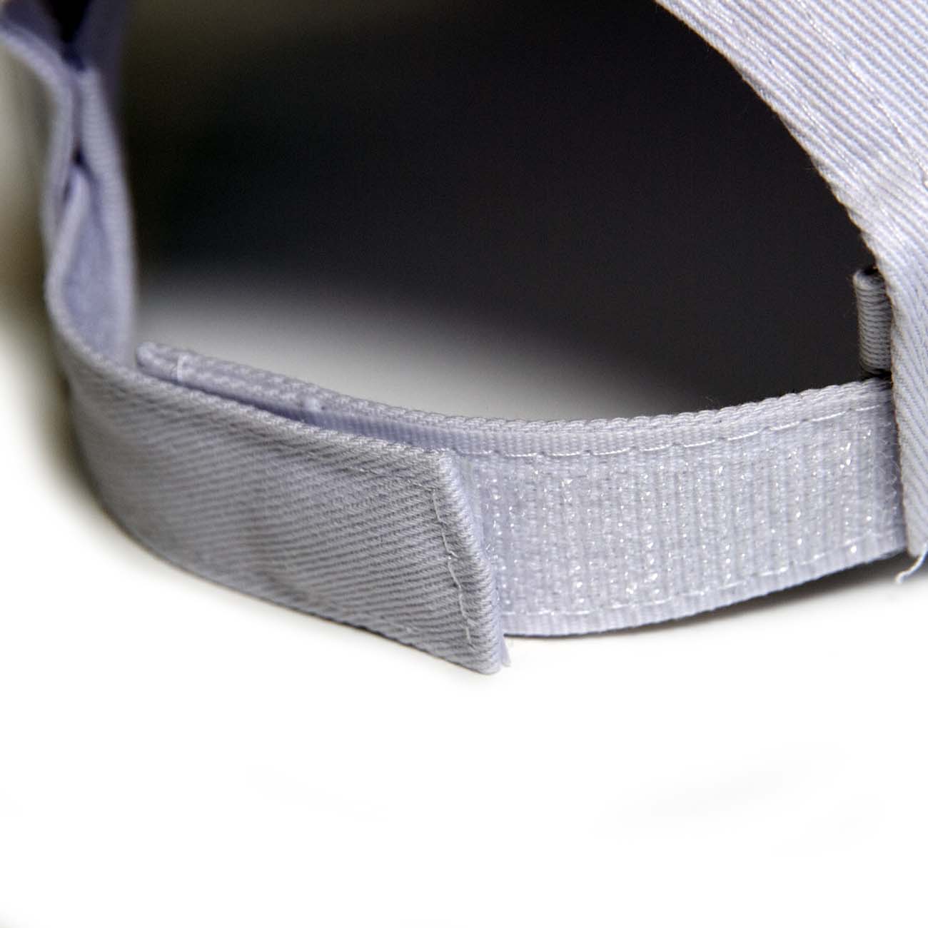 Close-up of the adjustable strap and velcro fastener on the back of a light gray cotton Boeing Starliner CST-100 Hat from The Boeing Store.