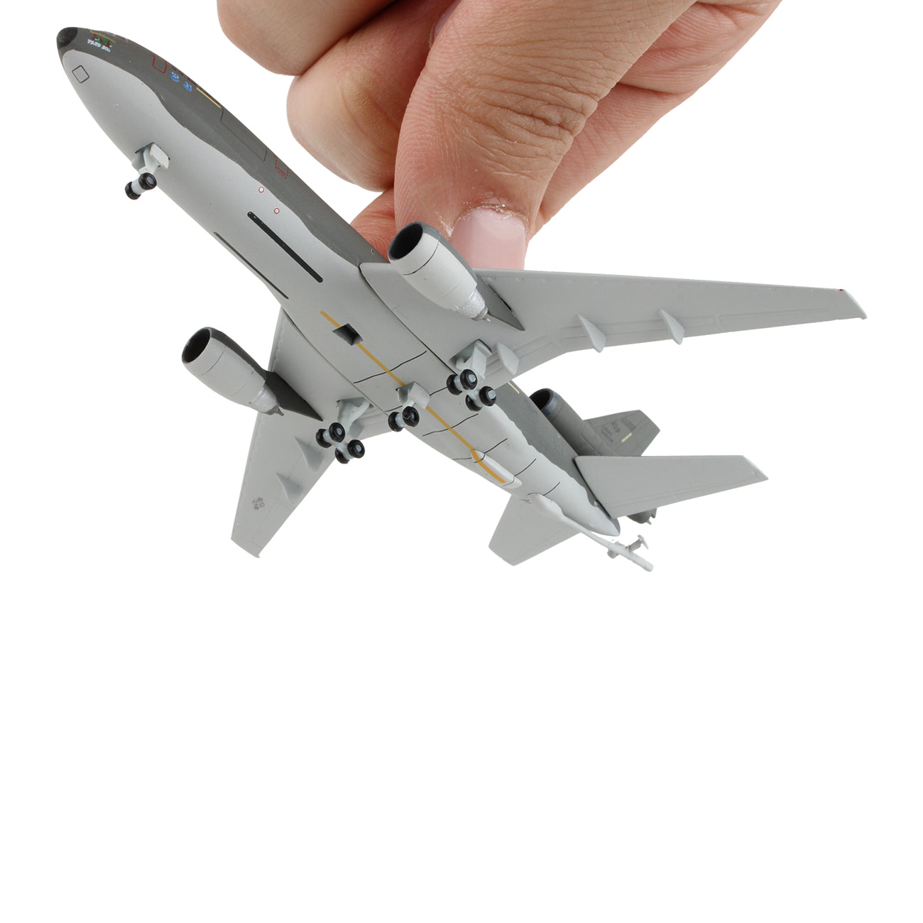 A hand holds the DARON Boeing KC-10A USAF 1:500 die-cast model by the tail against a white background, showcasing its detailed underside and landing gear.