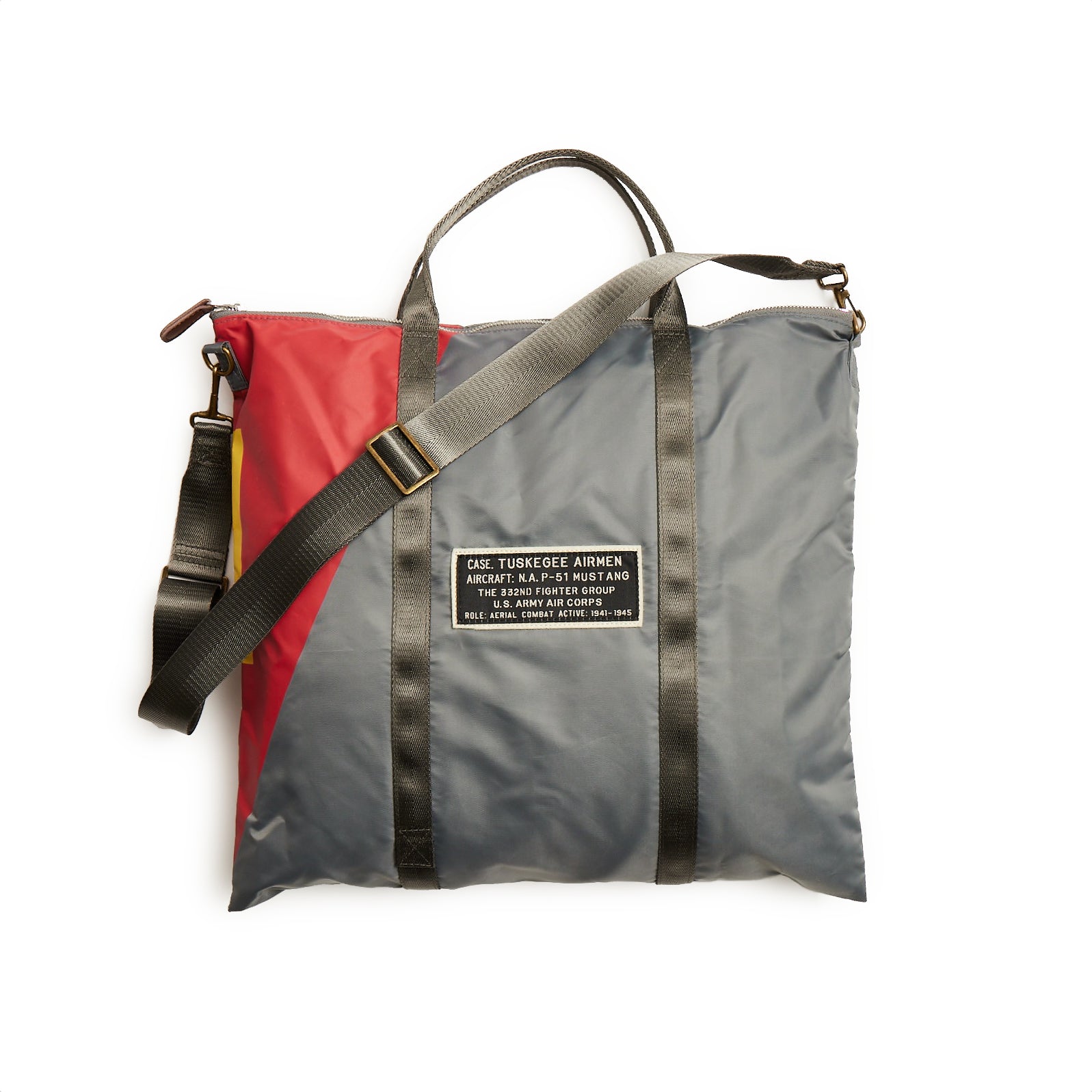 The Red Canoe Tuskegee Helmet Bag from The Boeing Store features a vibrant red and gray design with YKK zippers, black straps, and an adjustable shoulder strap. A bold black patch reads: CAKE TUSKEGEE AIRMEN ATTEMPT A FORCED LANDING MISSISSIPPI 1963.