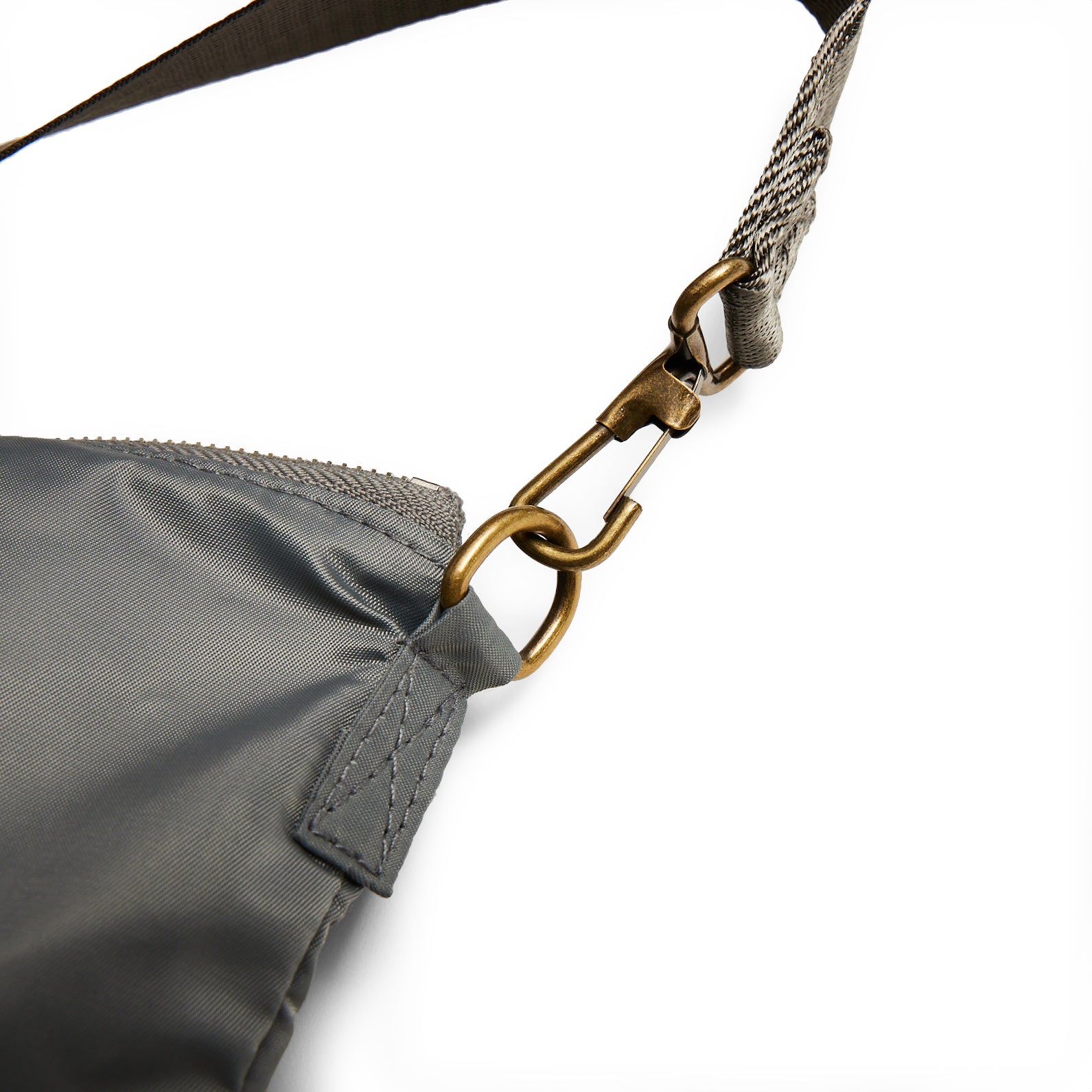 Close-up of the Red Canoe Tuskegee Helmet Bag by The Boeing Store, featuring a gray fabric with a gold-colored metal clasp and adjustable shoulder strap. Visible YKK zippers and stitching details highlight its design elements on a white background.
