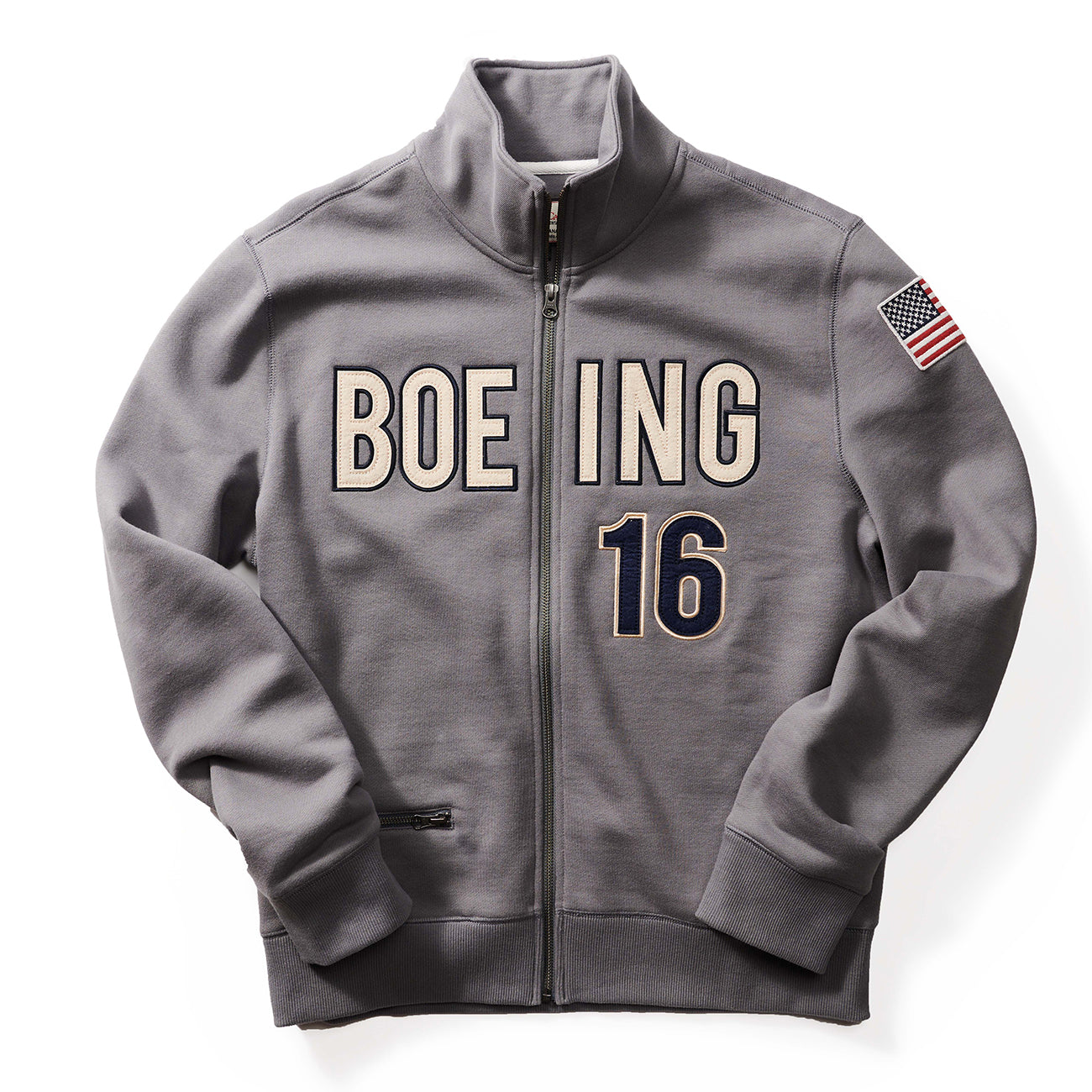 The Boeing Stores Red Canoe Boeing Full Zip Sweatshirt is a gray fleece jacket with BOEING 16 on the front, an American flag patch on the left sleeve, and a small zippered pocket on the right side.
