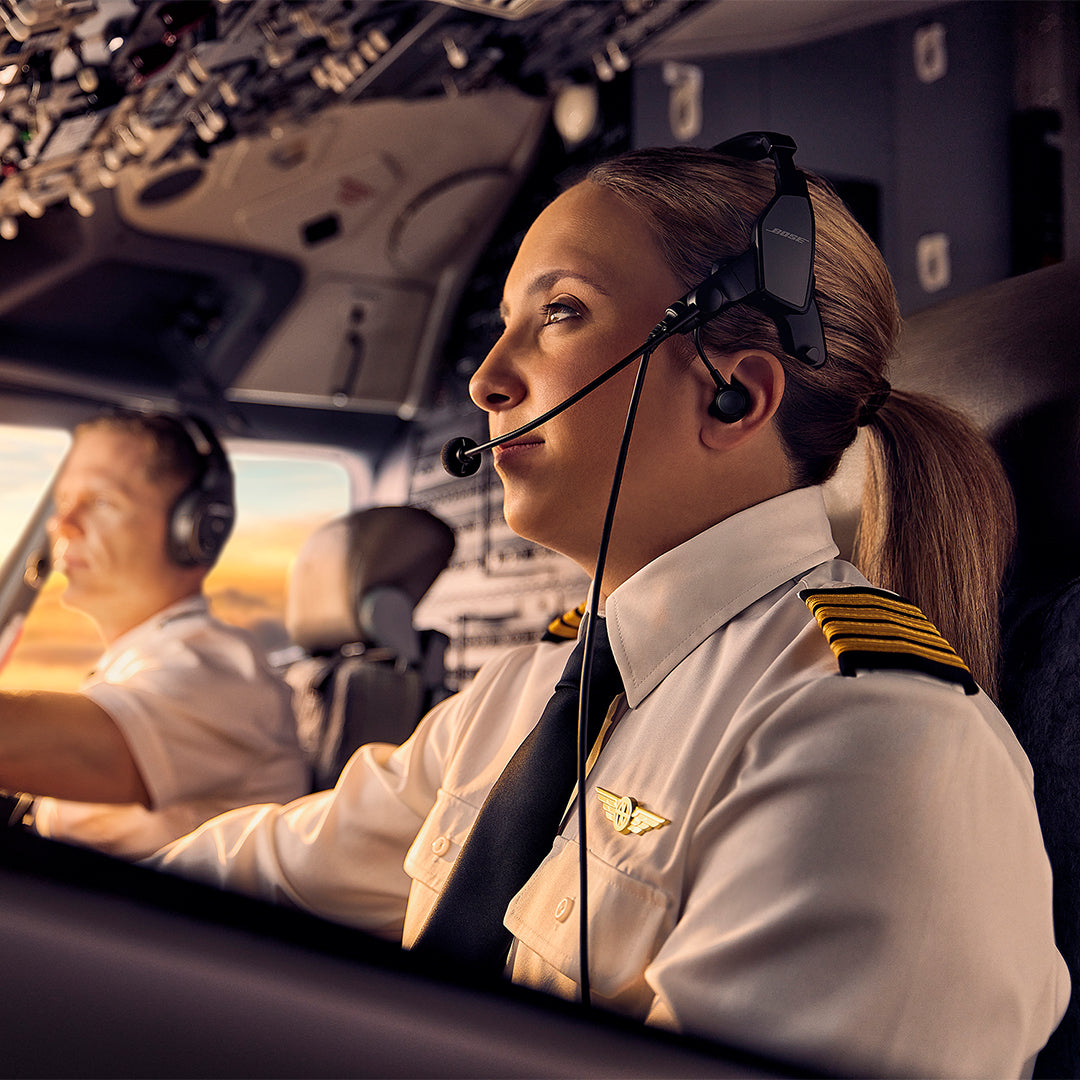 Product Feature section with female pilot wearing Bose ProFlight Series 2 Headset while flying a small plane. A male co-pilot is in the background wearing a Bose A30 headset.
