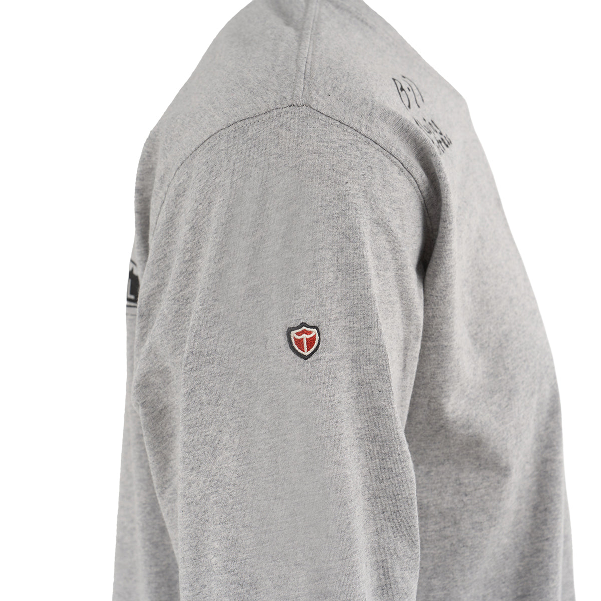 A close-up of a person wearing The Boeing Store’s Red Canoe Boeing Airplane Company Logo B-17 Long-Sleeve T-Shirt in light gray, featuring a small red and black shield-shaped logo on the left shoulder, set against a white background.