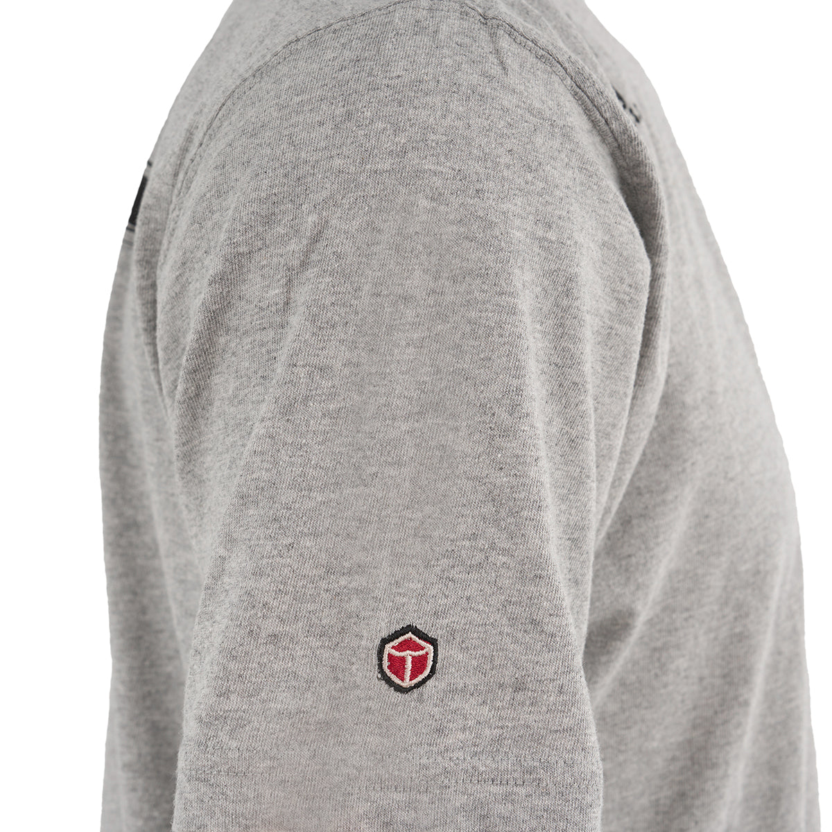 A close-up of a person wearing The Boeing Stores Red Canoe Boeing Airplane Company Logo B-17 T-Shirt in light gray, featuring a small red and black shield logo embroidered on the sleeve against a white background.