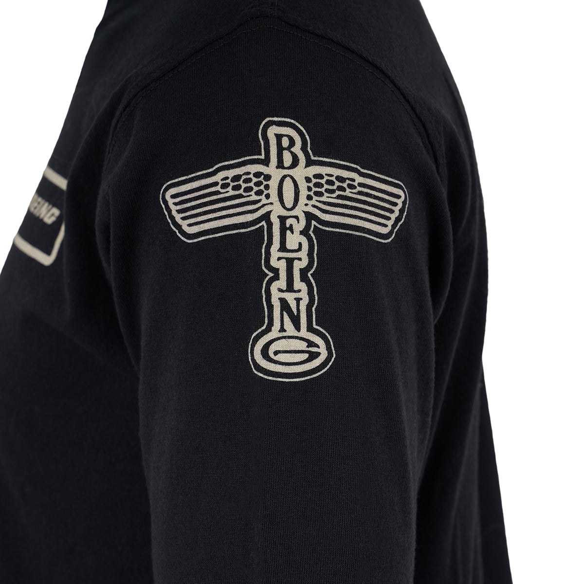 A close-up of The Boeing Store’s Red Canoe Boeing Long Sleeve T-Shirt sleeve, featuring a vintage airplane-shaped patch with “BOEING” written vertically.