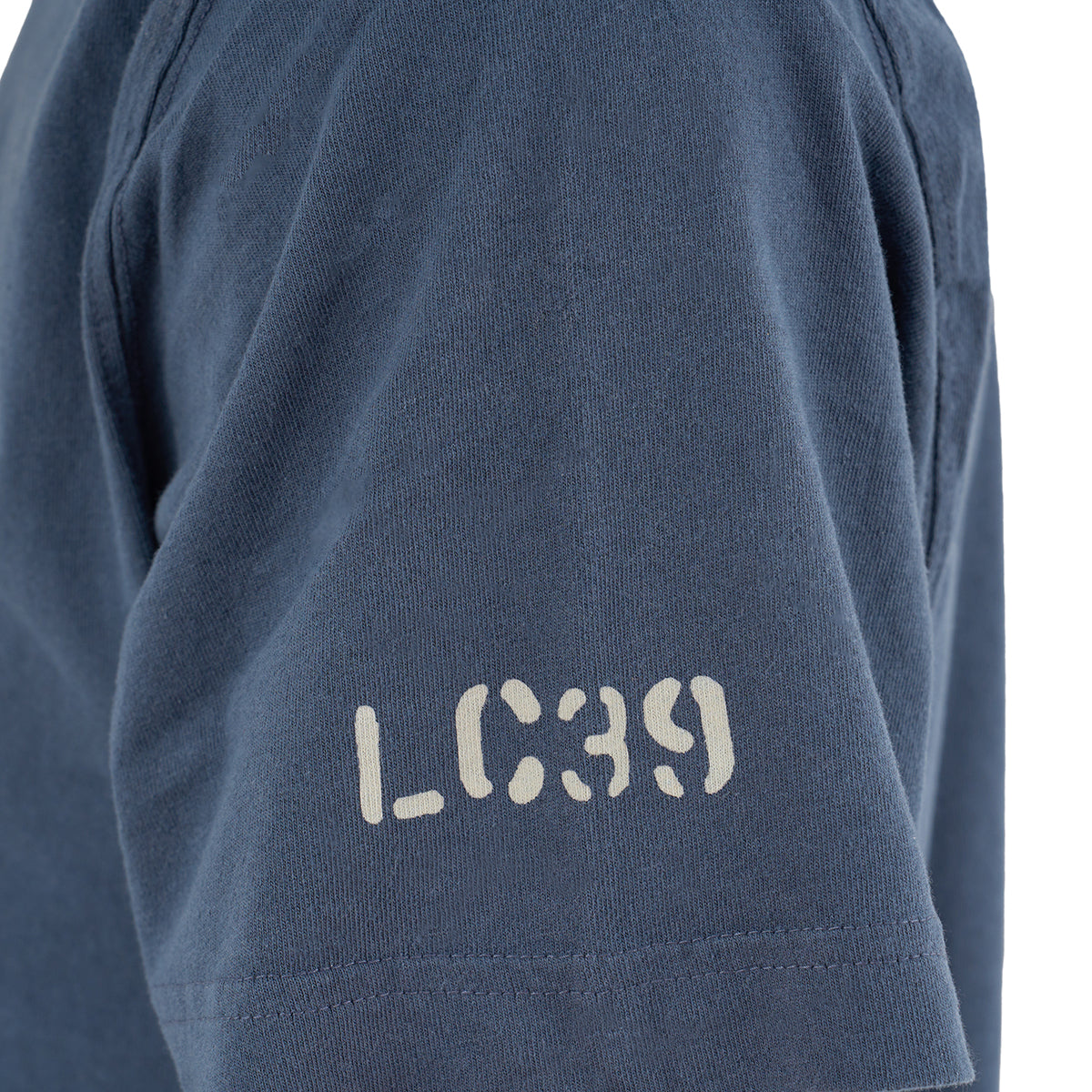Close-up of a person wearing The Boeing Store’s Red Canoe NASA Rocket Scientist T-Shirt, featuring LC39 in a stencil-style white font printed on the sleeve.