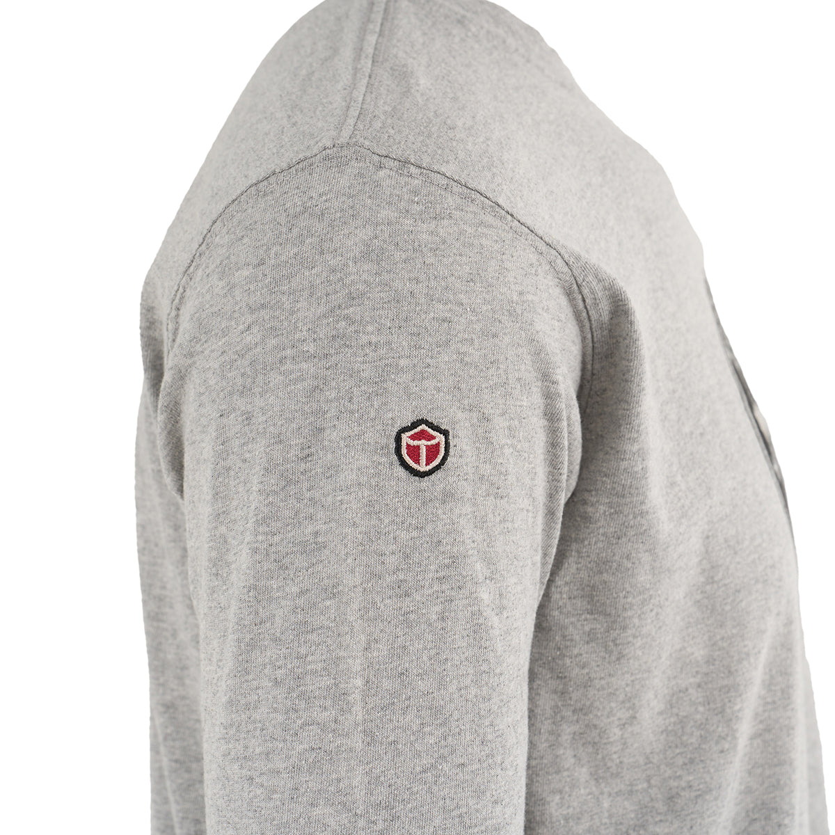A close-up side view of a person wearing The Boeing Store’s Red Canoe Tuskegee Airmen Long Sleeve T-Shirt in light grey, featuring a small shield emblem inspired by the legacy of the Tuskegee Airmen and the P-51 Red Tail Mustang.