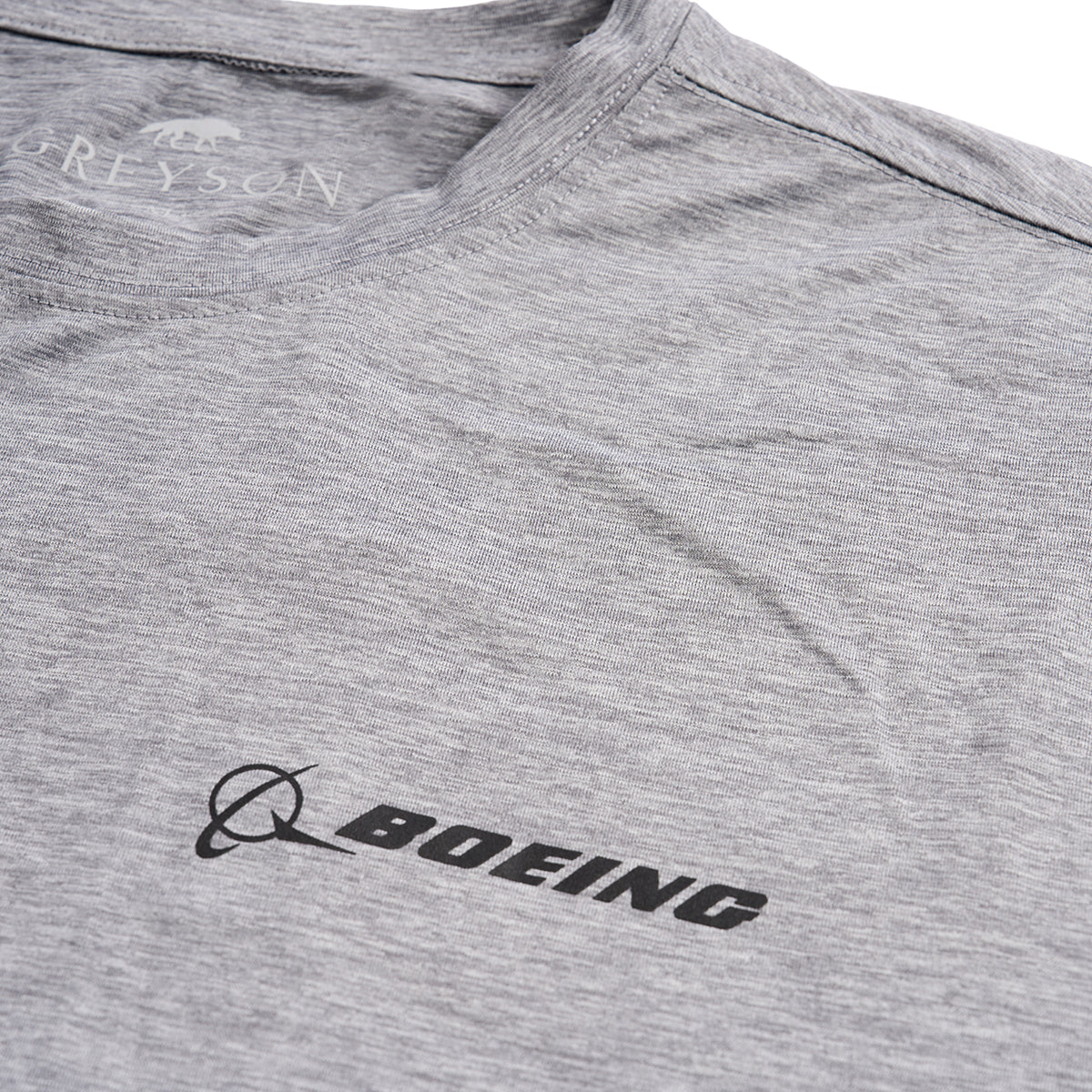 Close up of the black Boeing logo on the left chest on grey heather t-shirt.