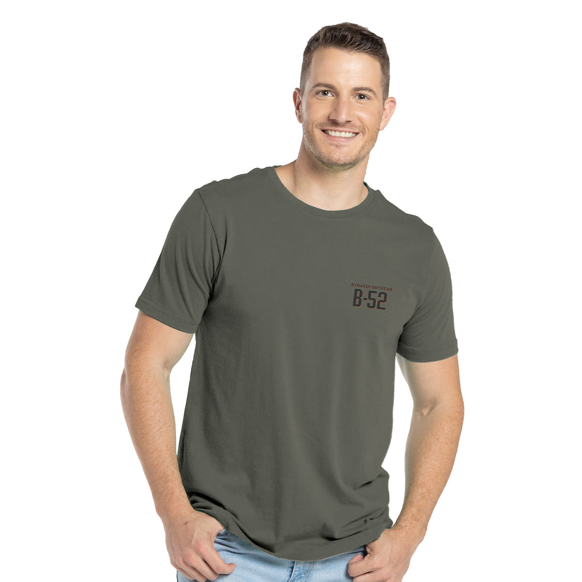 A smiling person wears a Boeing B-52 Mens T-Shirt in dark green cotton blend, with B-52 Stratofortress on the left side, paired with light blue jeans. Short brown hair complements the plain white background.