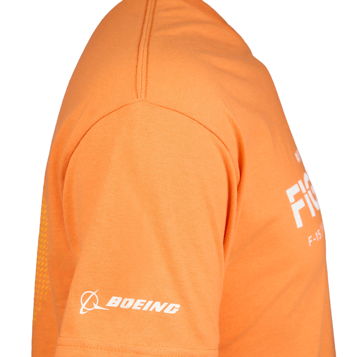 A close-up of a person wearing a Boeing Fighters QF-16 Unisex T-Shirt in orange, featuring a short sleeve with the white Boeing logo and a partial white text design on the chest.