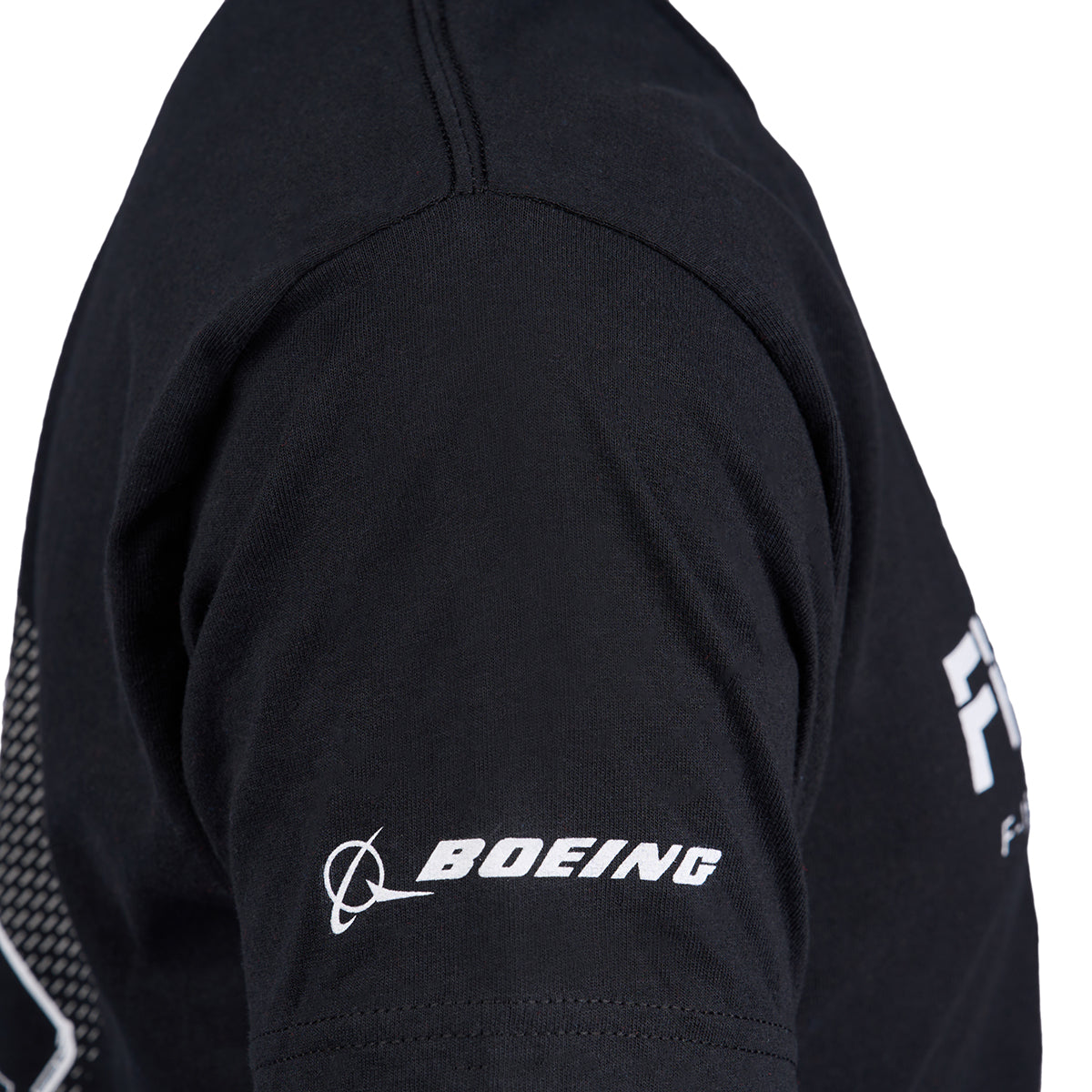 Someone is wearing a black Boeing Fighters F-15 Unisex T-Shirt with the Air Dominance Fighters logo in white on the sleeve.