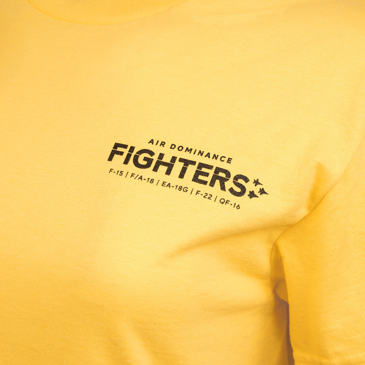 Boeings EA-18G Growler Unisex T-Shirt in yellow features Air Dominance Fighters in black on the chest, small text listing aircraft models including F-15, F/A-18, EA-18G Growler, F-22, QF-16. Decorative silhouettes of Boeing’s electronic warfare aircraft are adjacent.