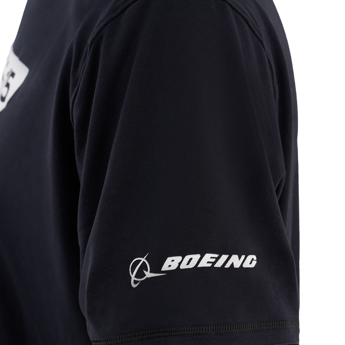 Close-up of the Boeing F-15 Eagle Velocity Unisex Tech Stretch T-Shirt by BOEING, featuring black moisture-wicking fabric, athletic fit, and a white Boeing logo on the sleeve inspired by the F-15 Eagle.