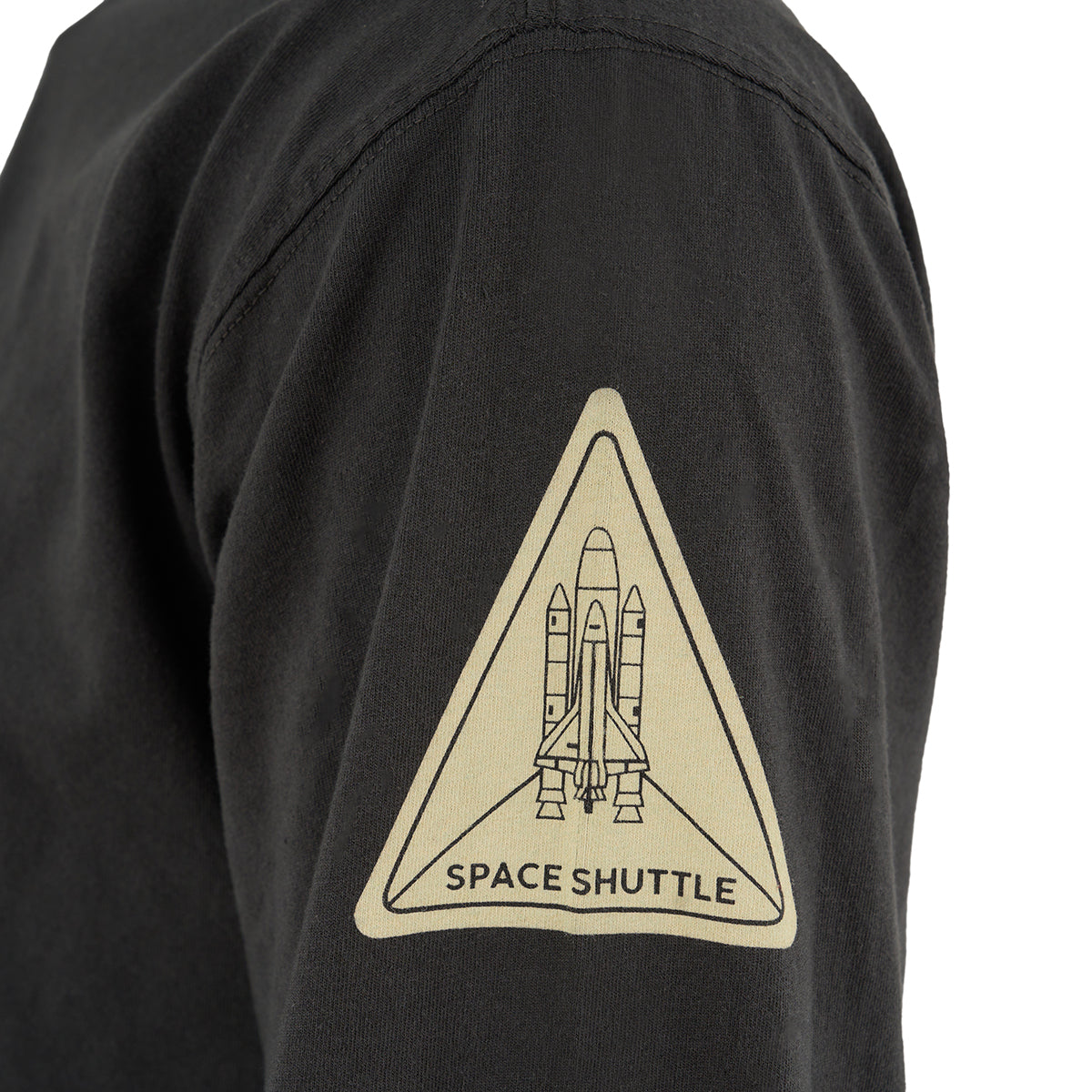 A close-up of the BOEING Red Canoe Space Shuttle Mens Long Sleeve T-Shirt, showcasing a triangular patch with a space shuttle, rockets, and SPACE SHUTTLE text—ideal for NASA fans.