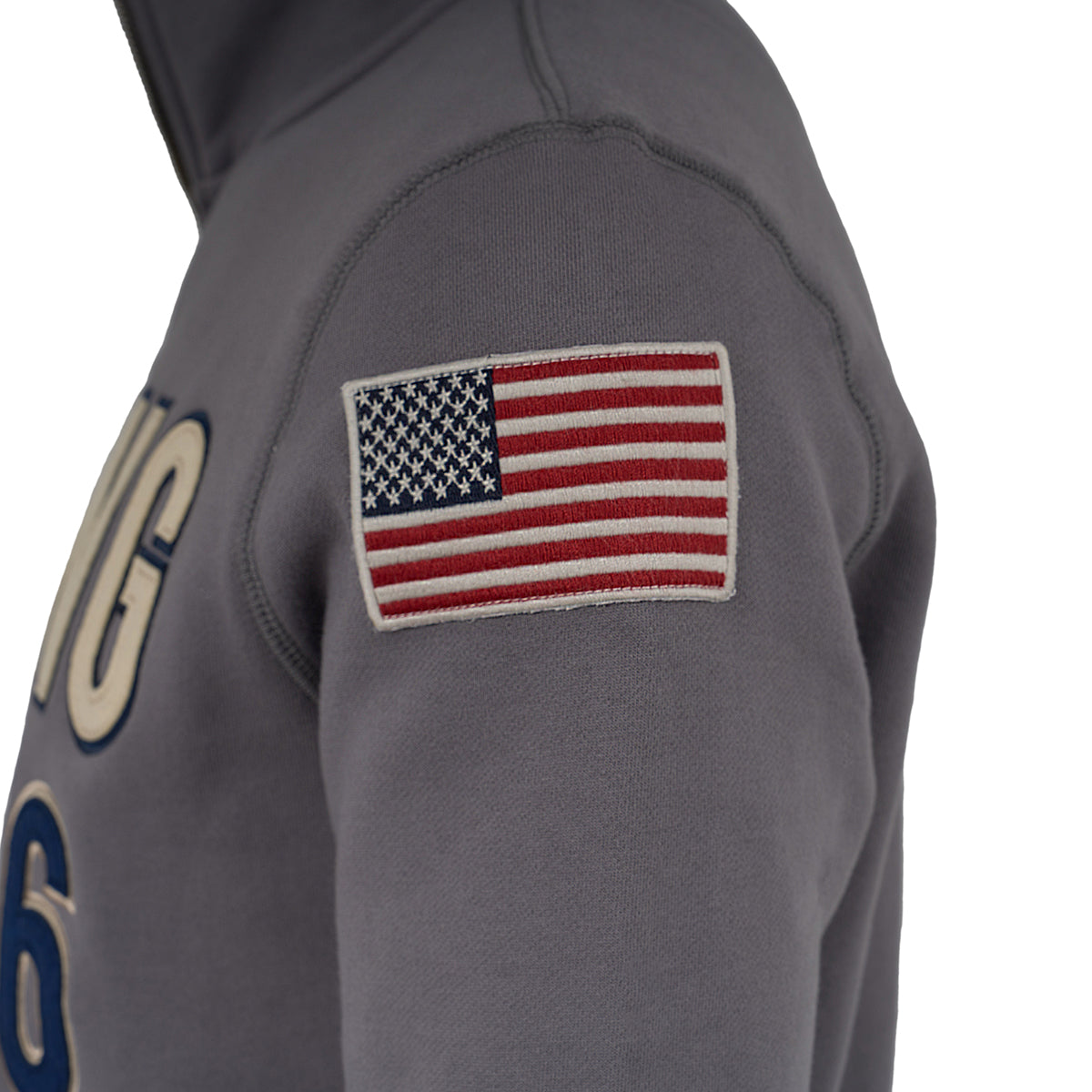 A close-up of the Red Canoe Boeing Full Zip Sweatshirt by The Boeing Store shows a gray fleece sleeve with a stitched American flag patch. The front displays partial text and the number 6 in a classic applique logo style.