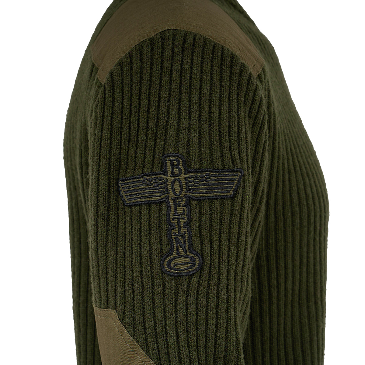 A close-up of the Red Canoe Boeing Ribbed Crewneck Sweater from The Boeing Store—a green acrylic wool sweater with dark shoulder and elbow patches, plus a blue BOEING winged emblem patch on the sleeve for modern style.