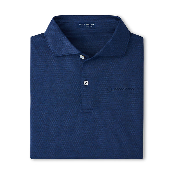 The Peter Millar Boeing Men’s Jukebox Performance Polo is a dark blue, four-way stretch shirt with a collar, two white buttons, and a subtle Boeing logo on the left chest. The inside collar label displays Peter Millar branding.