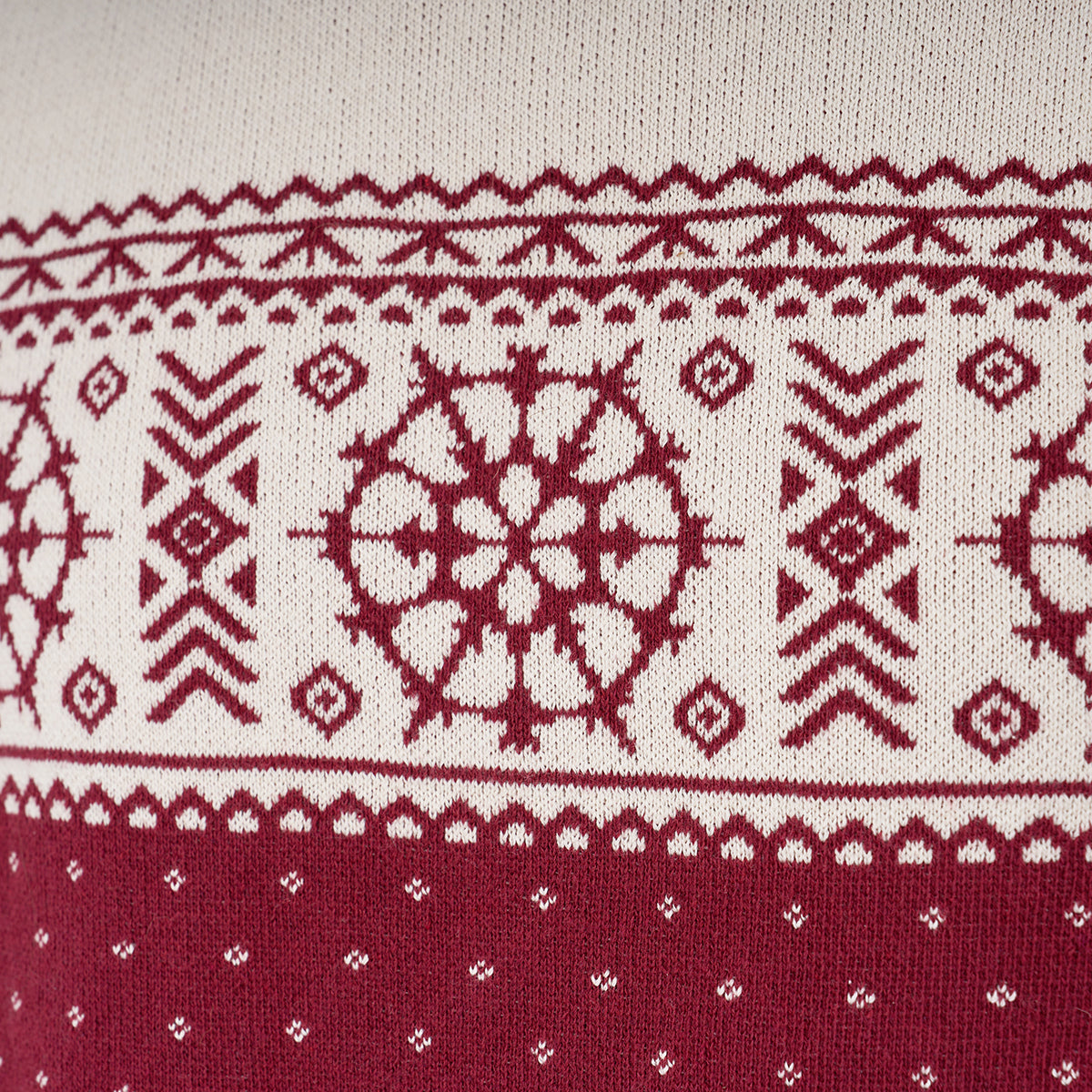 Close-up of a knitted fabric with red and white Nordic-inspired geometric patterns, reminiscent of star-like motifs on the Boeing 2025 Jet Snowflake Unisex Sweater by BOEING, showcasing symmetrical shapes, zigzags, and diamonds.