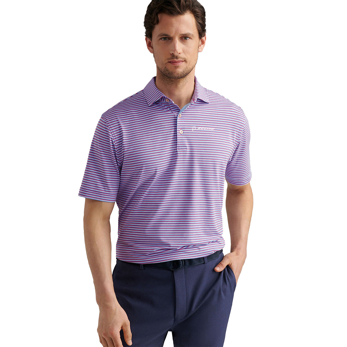 A man stands confidently with one hand in his pocket, wearing a purple and white striped Peter Millar Boeing Men’s Lenway Performance Polo by BOEING and dark blue pants.