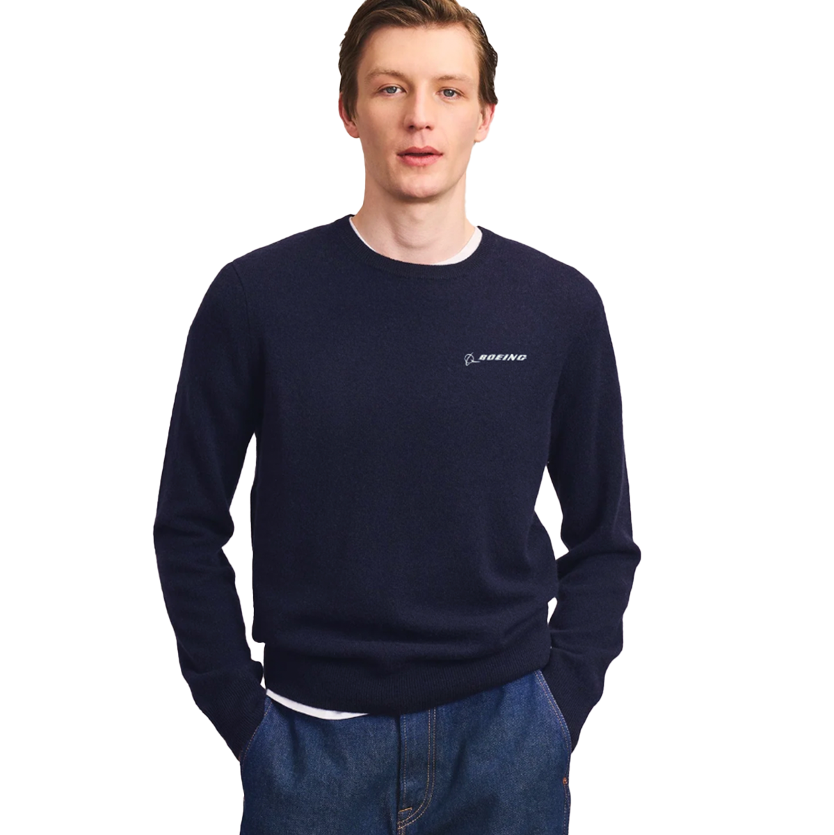 A man wearing the Boeing Signature Men’s Cashmere Sweater by BOEING in navy blue, paired with blue jeans, stands with his hands in his pockets against a white background.