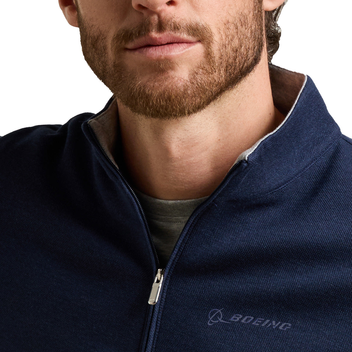 A close-up of a man wearing the Peter Millar Boeing Men’s Crown Comfort Knit Quarter-Zip in navy blue, featuring the Boeing logo on the chest and layered effortlessly for a coastal-inspired, casually sophisticated look. Only the lower half of his face and upper torso are visible, emphasizing the modern appeal and comfort of this BOEING signature piece.