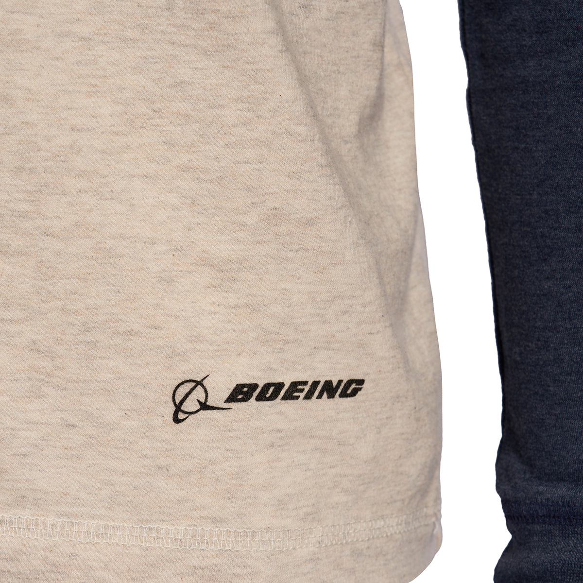 Close-up of Boeings beige Horizon Mens Long Sleeve T-Shirt showcasing a black Boeing Horizon logo near the bottom, complete with dark blue sleeves for an aviation-inspired look.