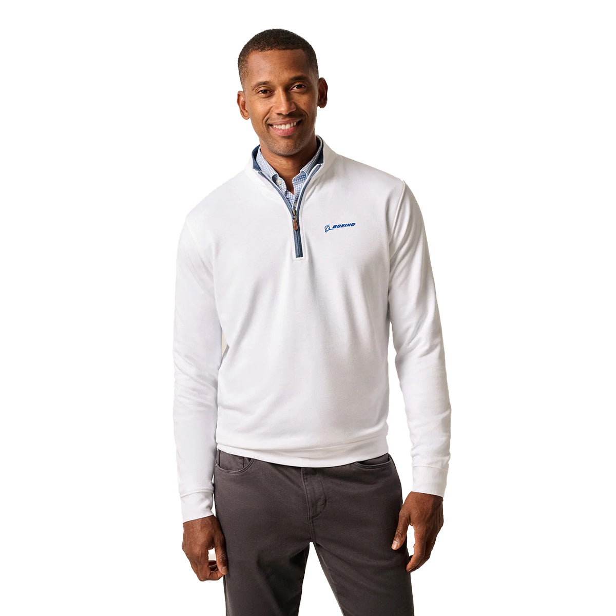 A man stands smiling with his hands by his sides, wearing a white BOEING johnnie-O Men’s Sully Quarter-Zip featuring a blue Boeing logo on the left chest, set against a plain white background.