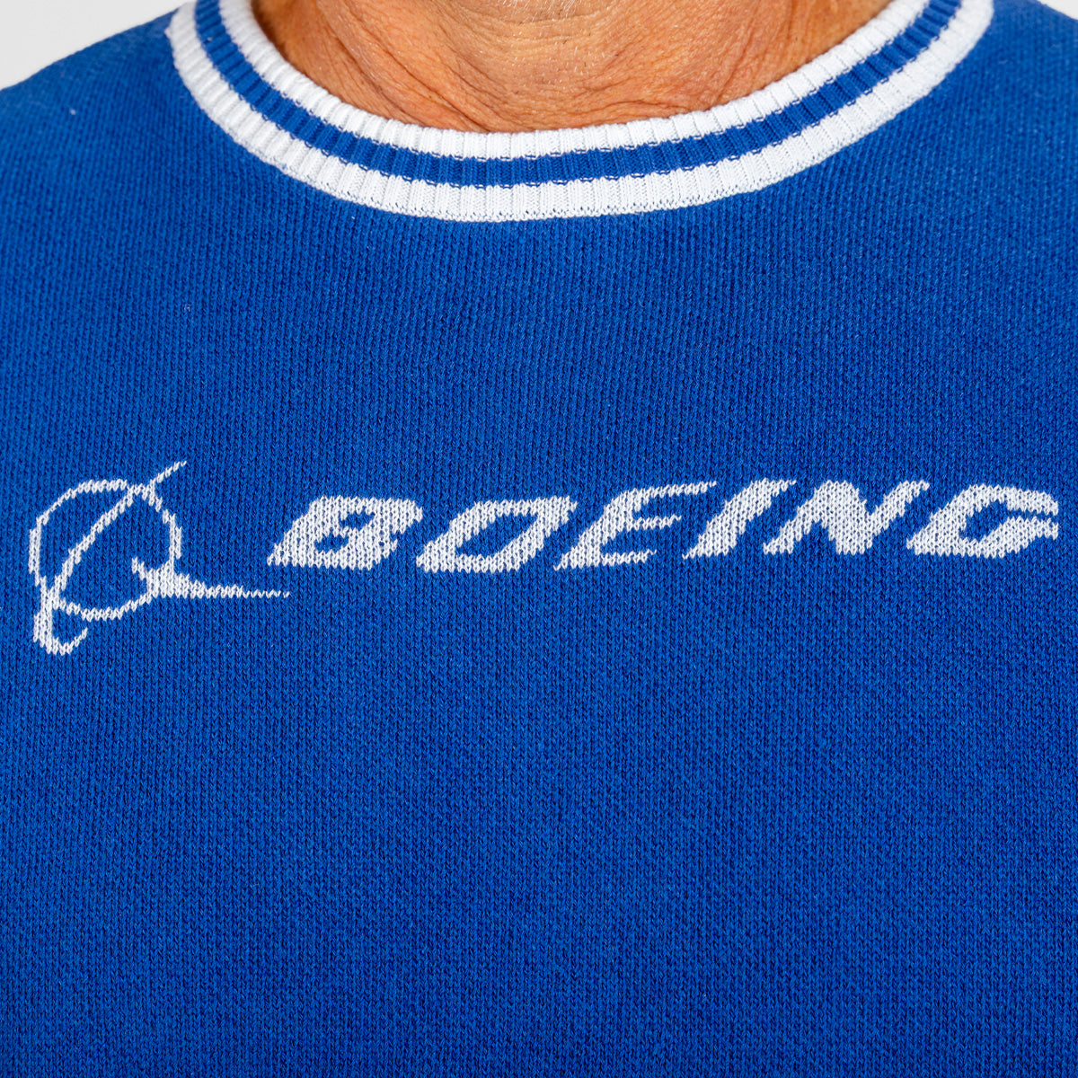 A close-up of a person wearing the Boeing Signature Unisex Andre Crewneck Sweatshirt by BOEING, featuring a blue quilted design with white trim and the Boeing logo elegantly knitted on the front, showcasing premium apparel style.