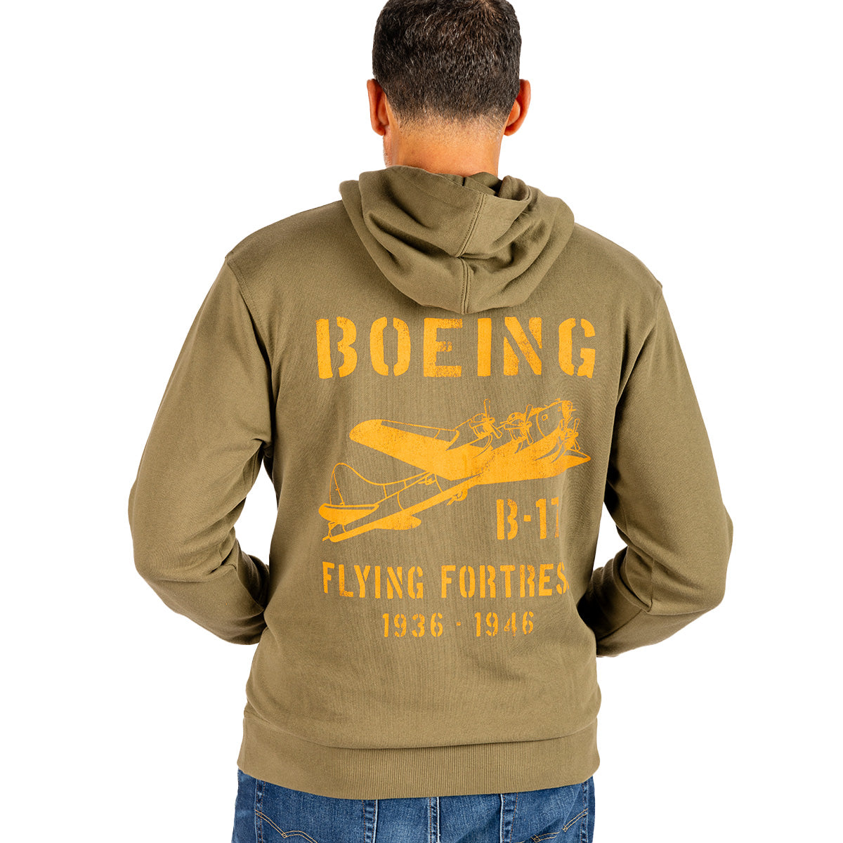 Wearing the Boeing Heritage B-17 Flying Fortress Unisex Hoodie by BOEING, an individual stands with their back to the camera, displaying an olive green hoodie featuring a graphic of a yellow airplane and the text “BOEING B-17 FLYING FORTRESS 1936-1946” on the back. This timeless aviation apparel honors Boeing’s storied legacy.