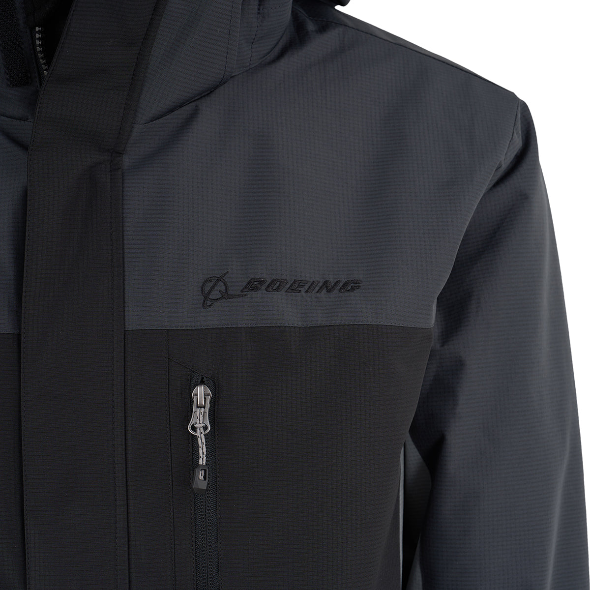 Close-up of the Boeing Men's Trifecta Ripstop Jacket by BOEING, featuring water resistance, a zippered chest pocket, subtle textured ripstop fabric, high collar, and an embroidered black Boeing logo on the upper left.