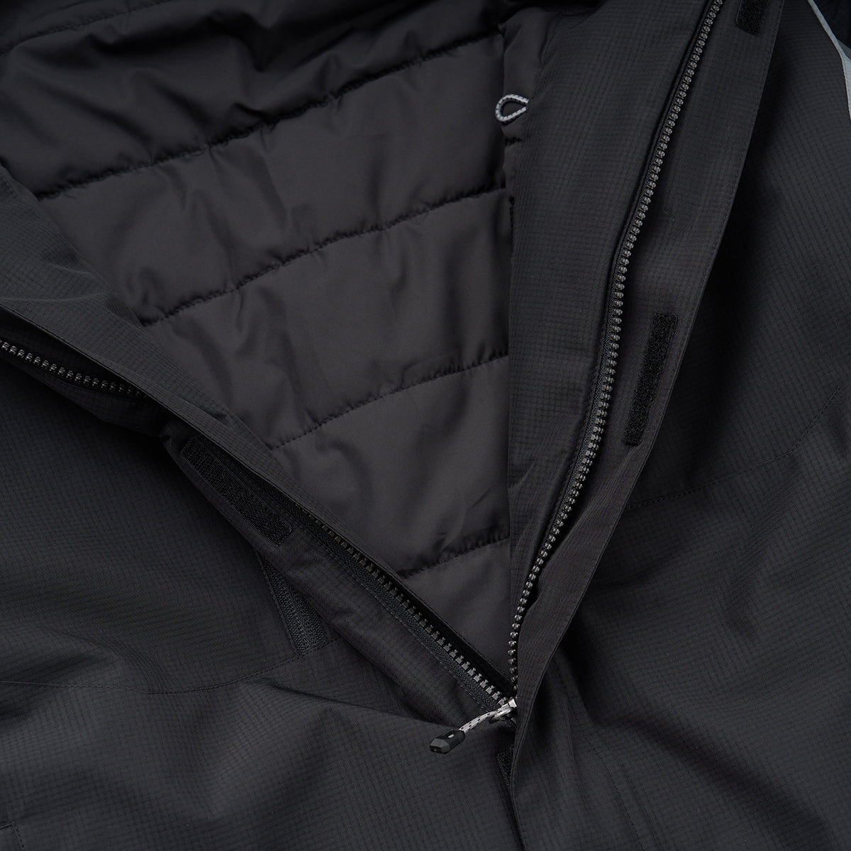 Close-up of the Boeing Men's Trifecta Ripstop Jacket by BOEING, featuring a partially unzipped front that reveals its padded, quilted inner lining and textured, water-resistant fabric detailing.