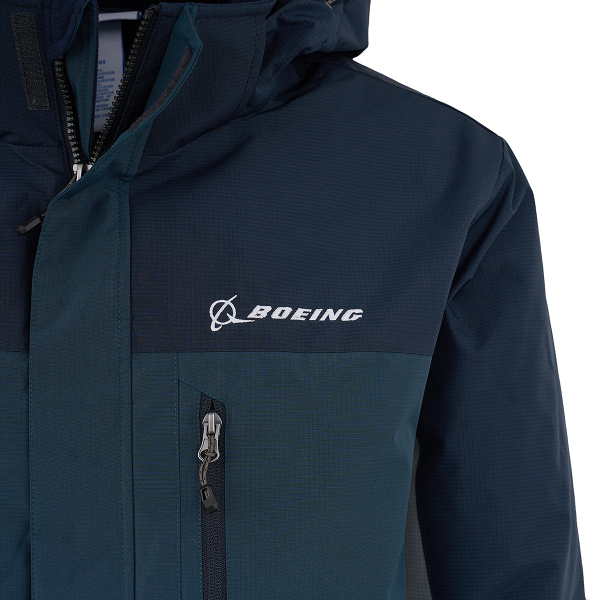 Close-up of the Boeing Men's Trifecta Ripstop Jacket by BOEING, dark blue with a hood, water-resistant ripstop fabric, white embroidered logo and name on the chest, and a zippered front pocket.