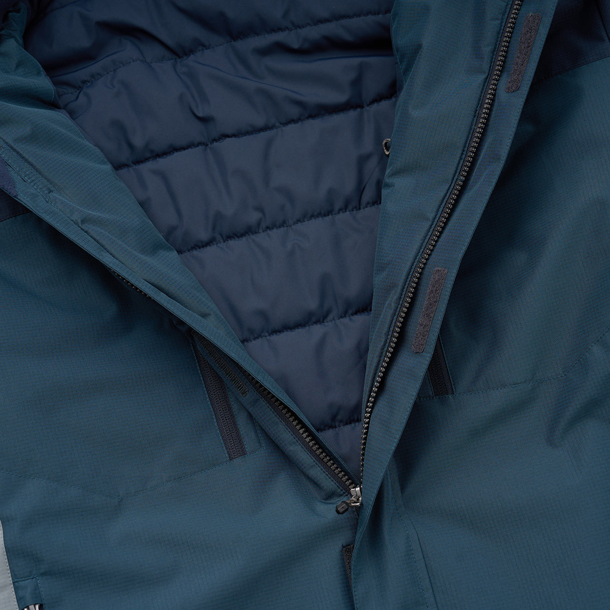 Close-up of the BOEING Men's Trifecta Ripstop Jacket in dark blue, featuring water-resistant fabric with a subtle sheen, visible stitching, quilted inner lining, and zippered side pockets. The jacket is partially unzipped to reveal its interior.