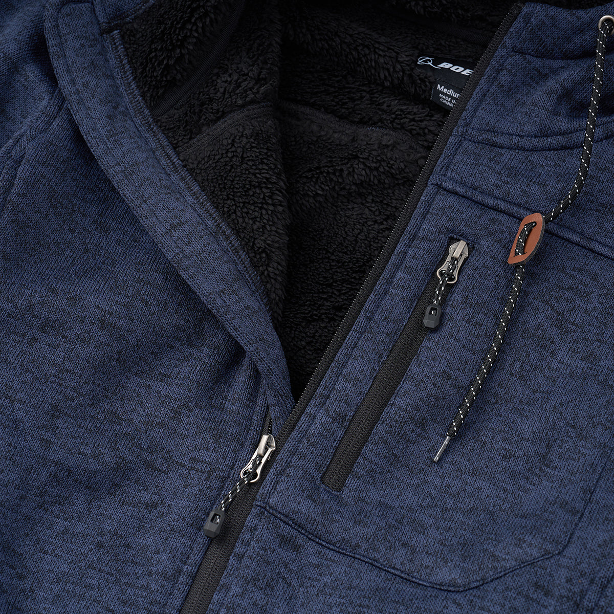 Close-up of the Boeing Men's Full-Zip Fleece Sweater by BOEING—features a blue zip-up design, soft black fleece lining, two zippered chest pockets, a branded pull cord, and subtle Boeing logo detailing for cozy hoodie-inspired style.