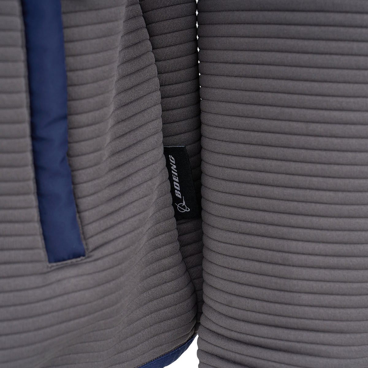 Close-up of the Boeing Men's Ottoman Quilted Knit Jacket, featuring ribbed gray fabric, a vertical navy trim on the left, and a small black Boeing tag sewn into the seam.