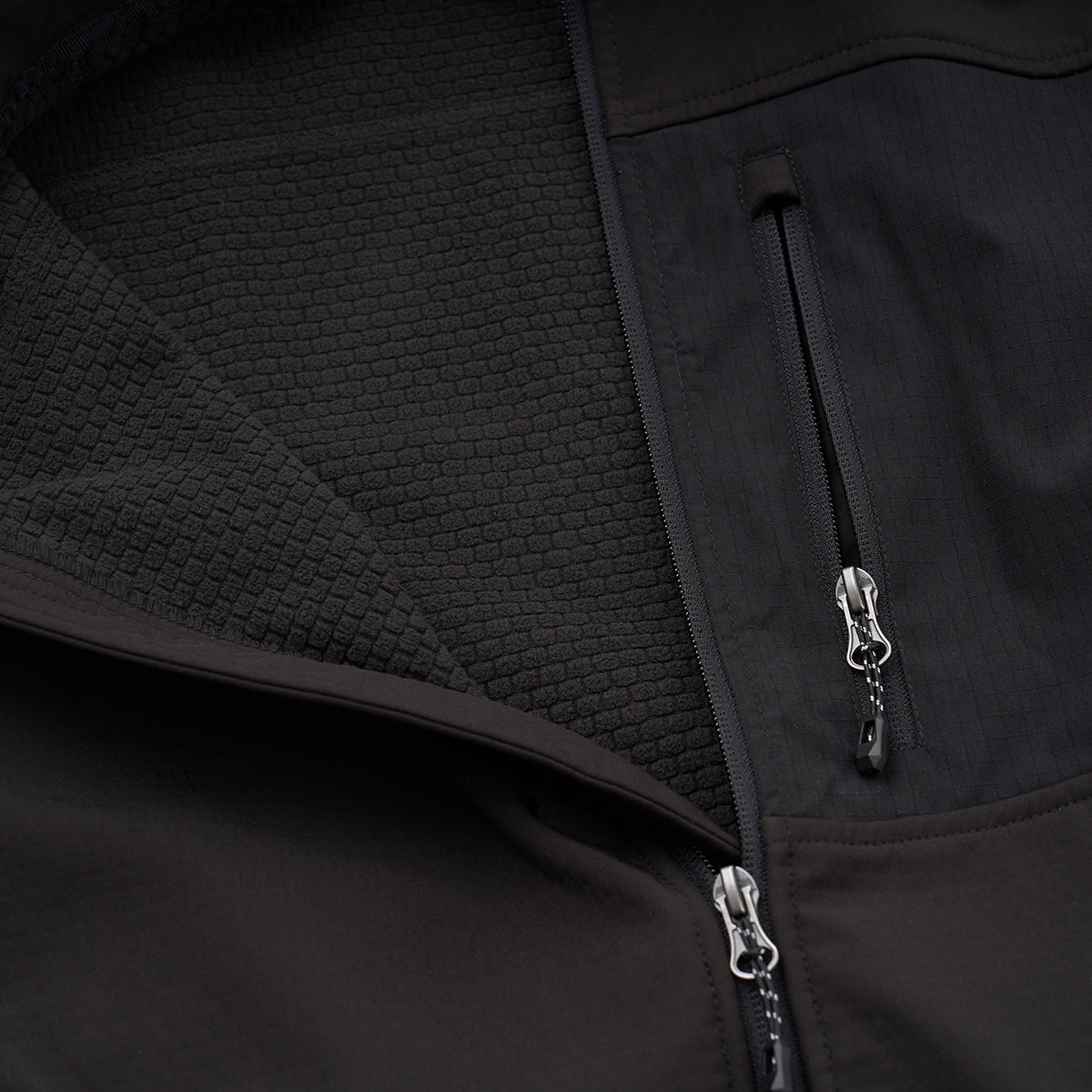 Close-up of the BOEING Men's Softshell Brick Jacket shows its textured hexagonal inner lining and two partly open front zippers. The recycled shell feels soft, water resistant, and insulated for warmth.