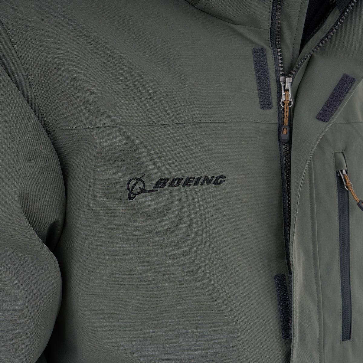 Close-up of the Boeing Men's 3-in-1 Systems Jacket by BOEING, featuring a zippered pocket and black embroidered Boeing logo on the chest—ideal versatile outerwear for all-weather protection.