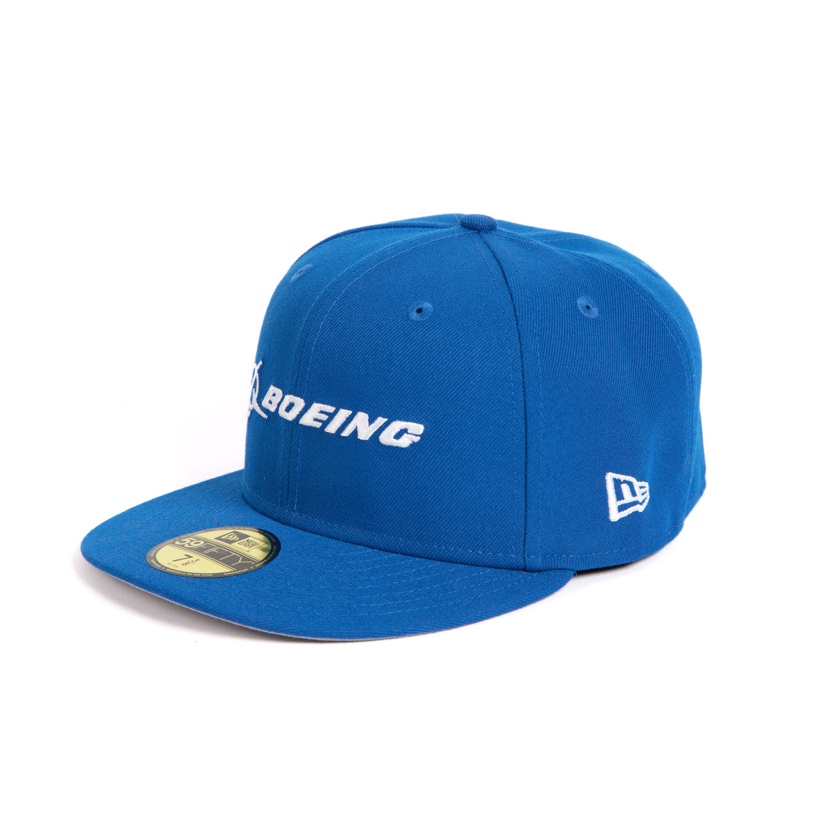 The New Era 59FIFTY Boeing Signature Logo Hat from The Boeing Store is a blue fitted cap with a flat brim. Boeing is prominently embroidered in white on the front, with a small logo on the side and a gold size sticker beneath the brim.