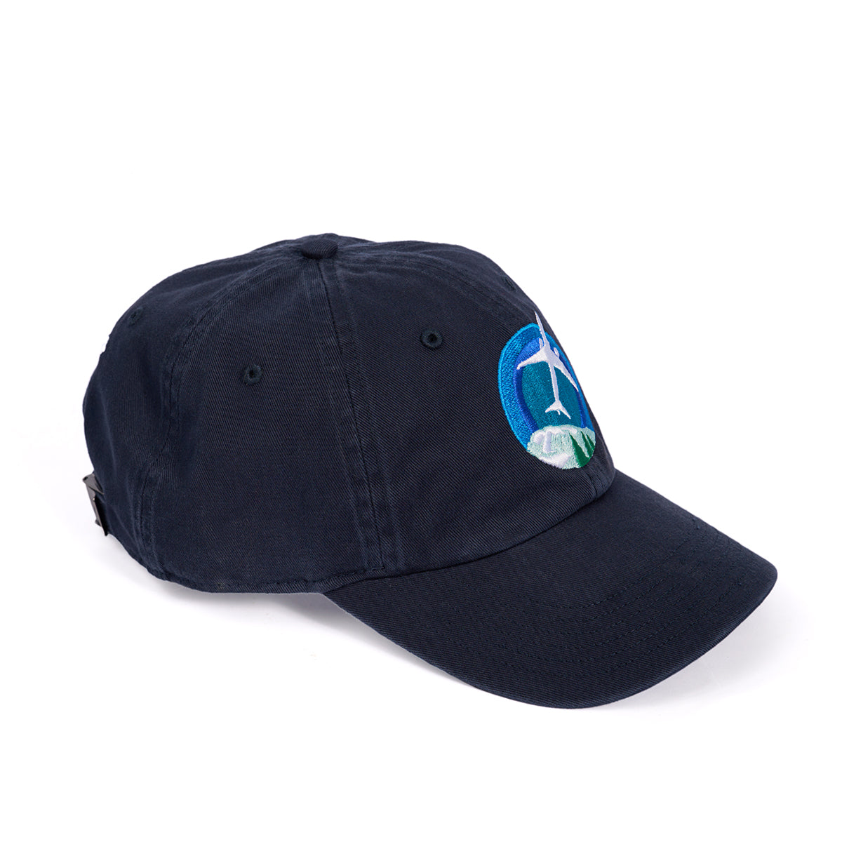 The Boeing 777X Skyward Hat features a navy blue color, curved brim, and adjustable backstrap. The front embroidery displays a wind turbine and green hills within a blue circle, inspired by the horizons viewed from a Boeing 777X.