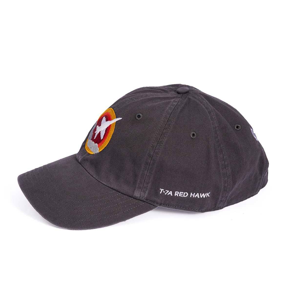 The Boeing T-7A Red Hawk Skyward Hat features a dark design with an embroidered bird emblem in a red and yellow circle on the front, T-7A RED HAWK white text on the side, and an adjustable backstrap for comfort.