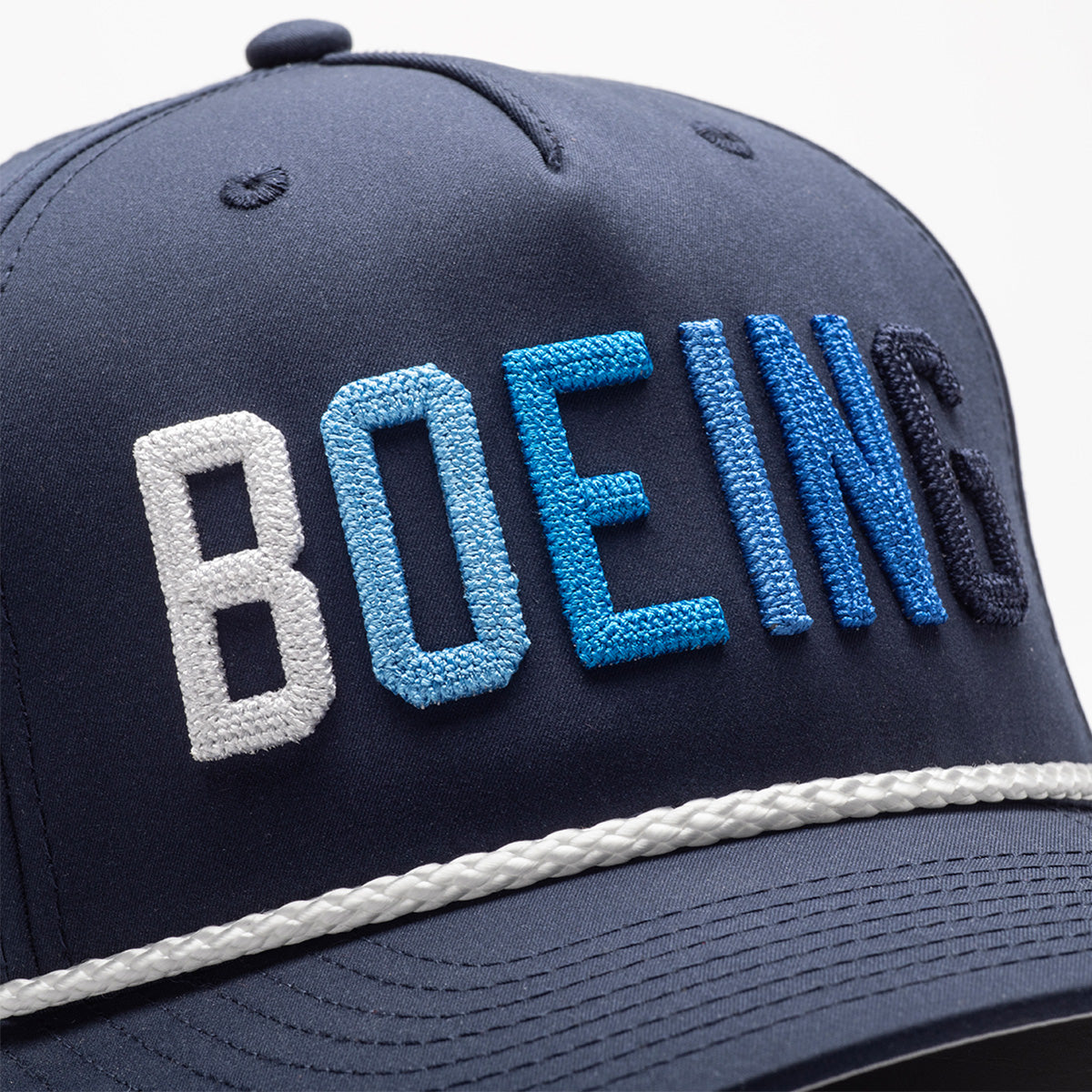 The Richardson Boeing Golf Hat by BOEING features navy performance polyester, gradient blue and white BOEING embroidery on the front, and a white braided rope above the brim—a stylish choice for golf.