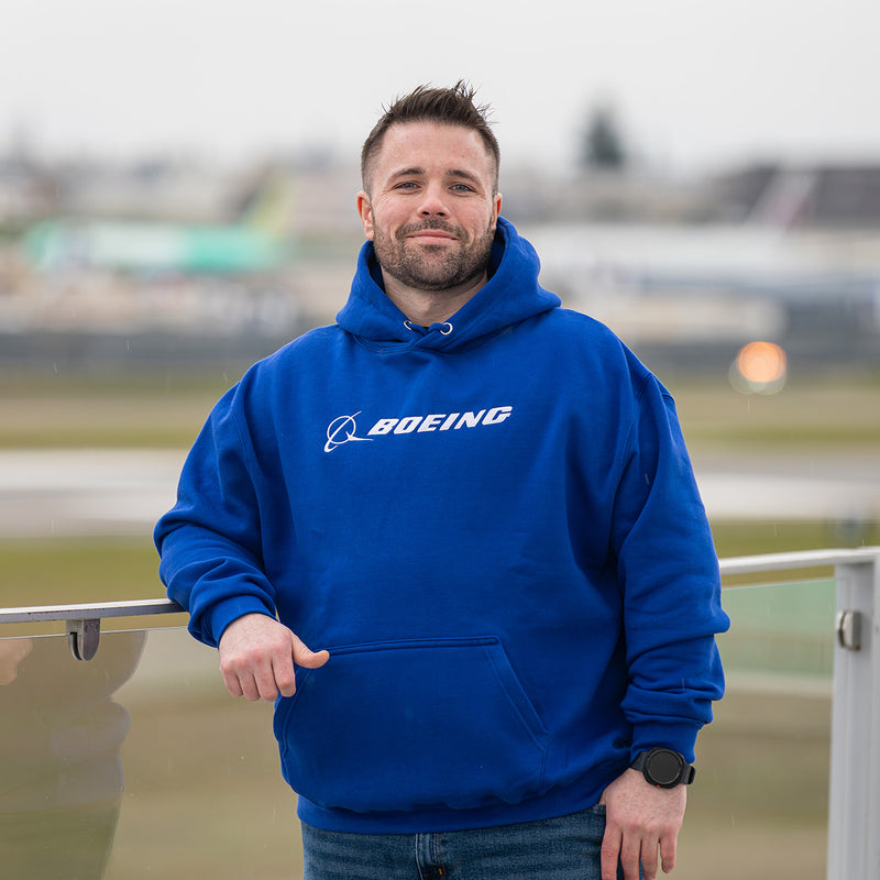 man wearing a blue Boeing signature hoodies with airplanes in the background